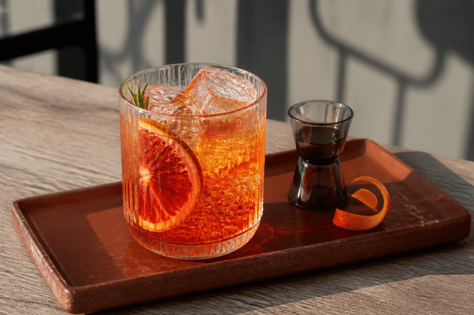 Aperol Spritz med blodappelsin og store isterninger i lavt riflet glas på terracotta-bakke