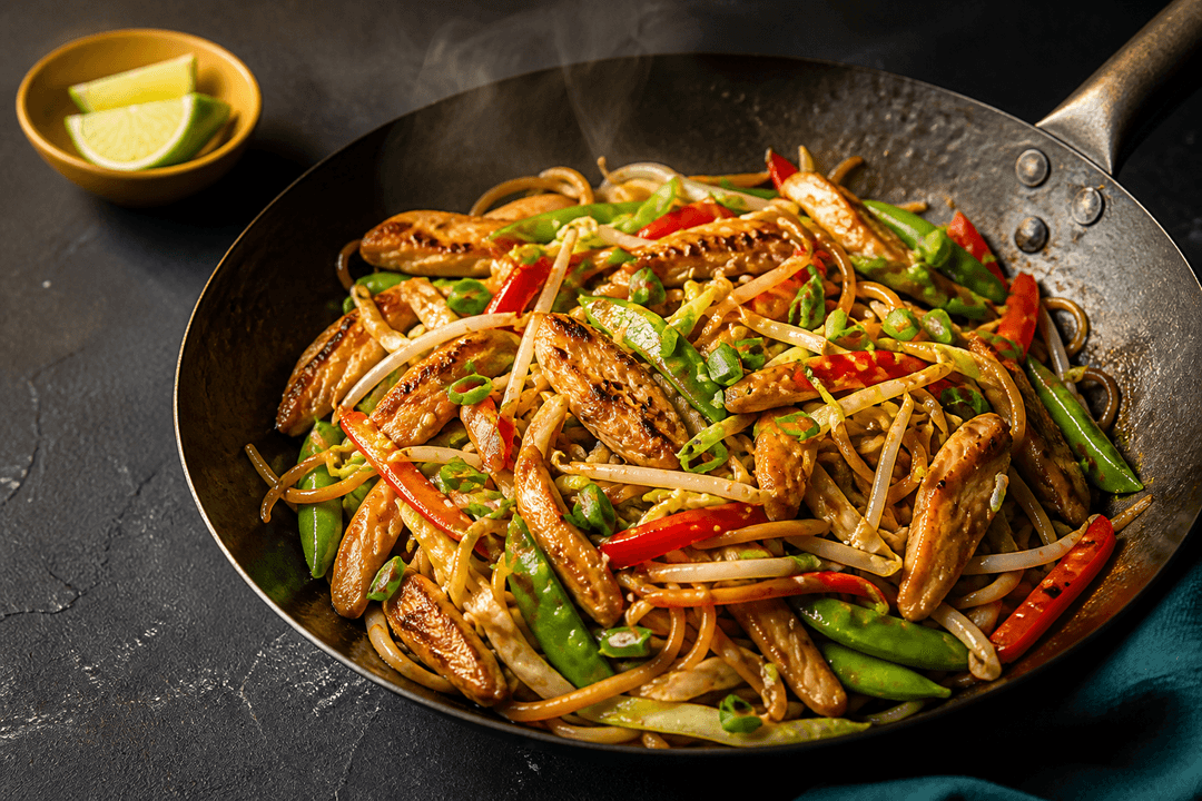 Wokstegt chow mein med karamelliseret kylling, spidskål, rød peber, sukkerærter og bønnespirer i mørk stålwok