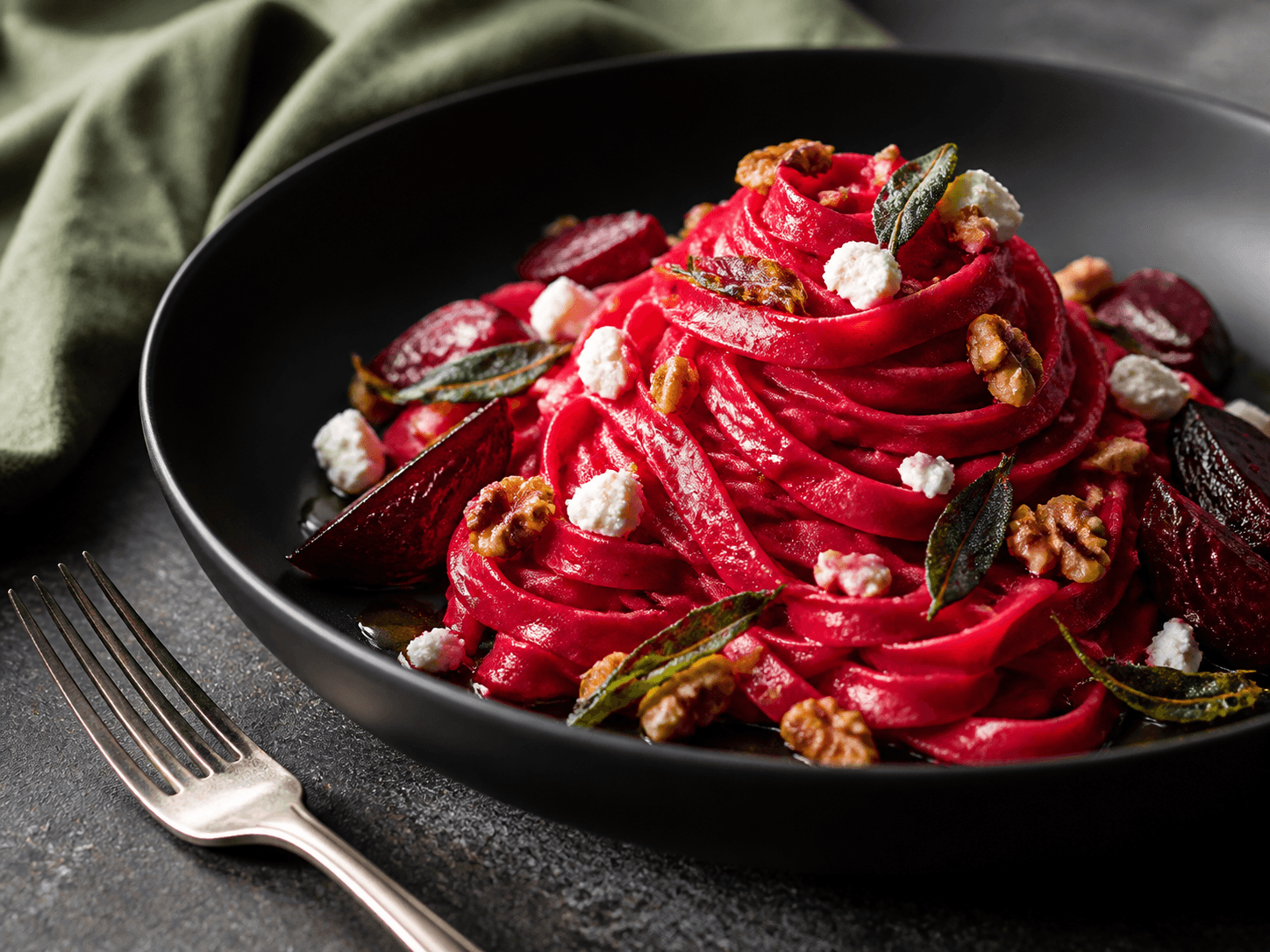 Blank magenta tagliatelle med ristet rødbedesauce, rødbedebåde, gedeost, valnødder og sprød salvie i mat sort skål