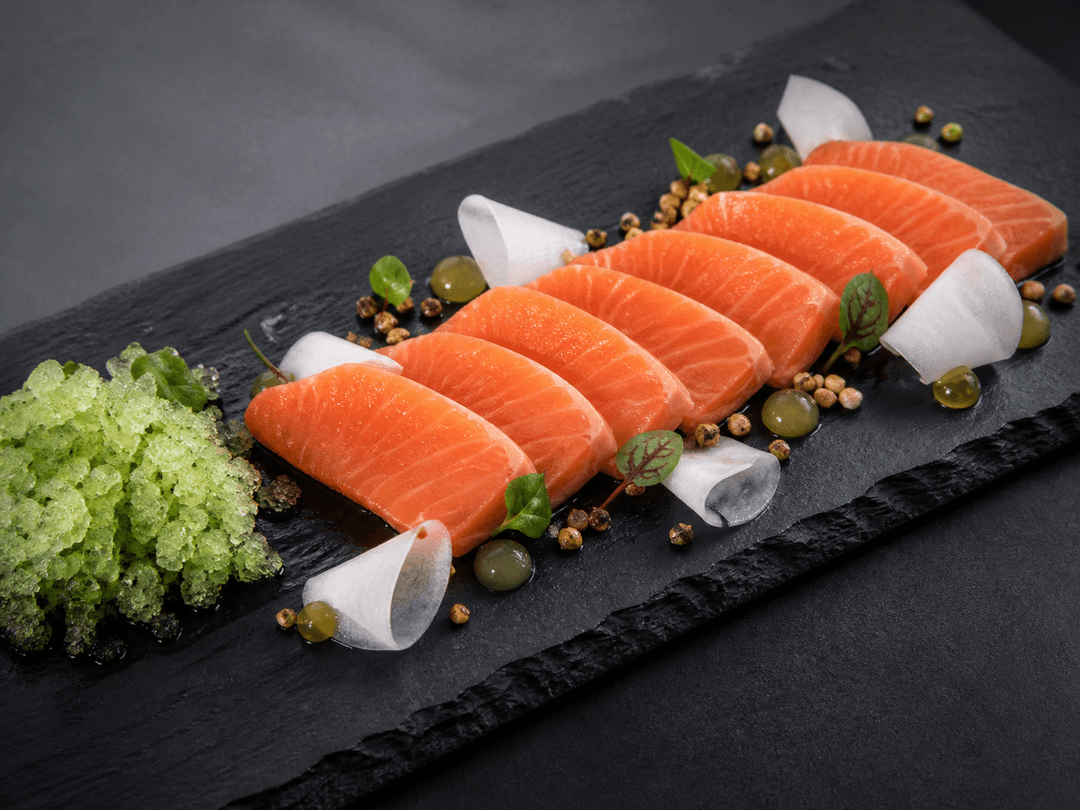 Lang mørk skifer med otte tykke skiver laksesashimi, grøn agurk-shisogranita, syltet daikon, yuzu-tamarigel og ristet boghvede