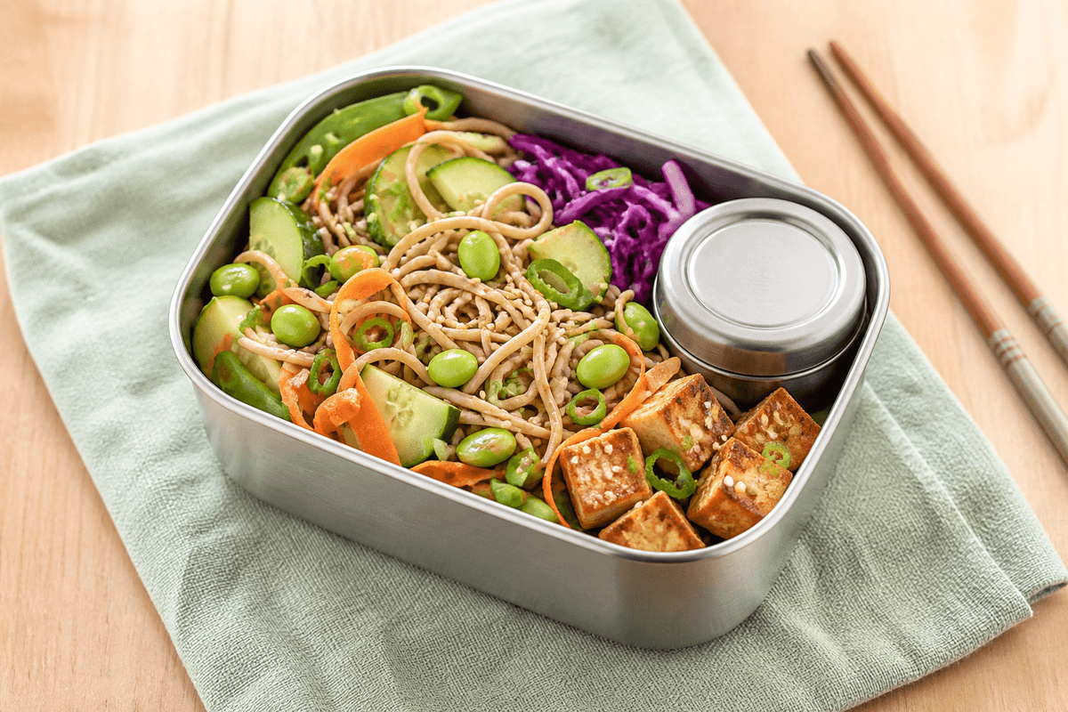 Stålbento med kolde sobanudler, brunet sesamtofu, edamame, agurk, gulerod, lilla kål, sukkerærter, forårsløg og separat sojadressing