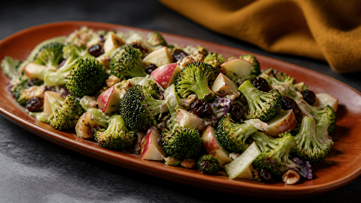 Brændt orange fad med ristede broccolibuketter, æble, rødkål, tranebær, hasselnødder og cremet senneps-nøddedressing