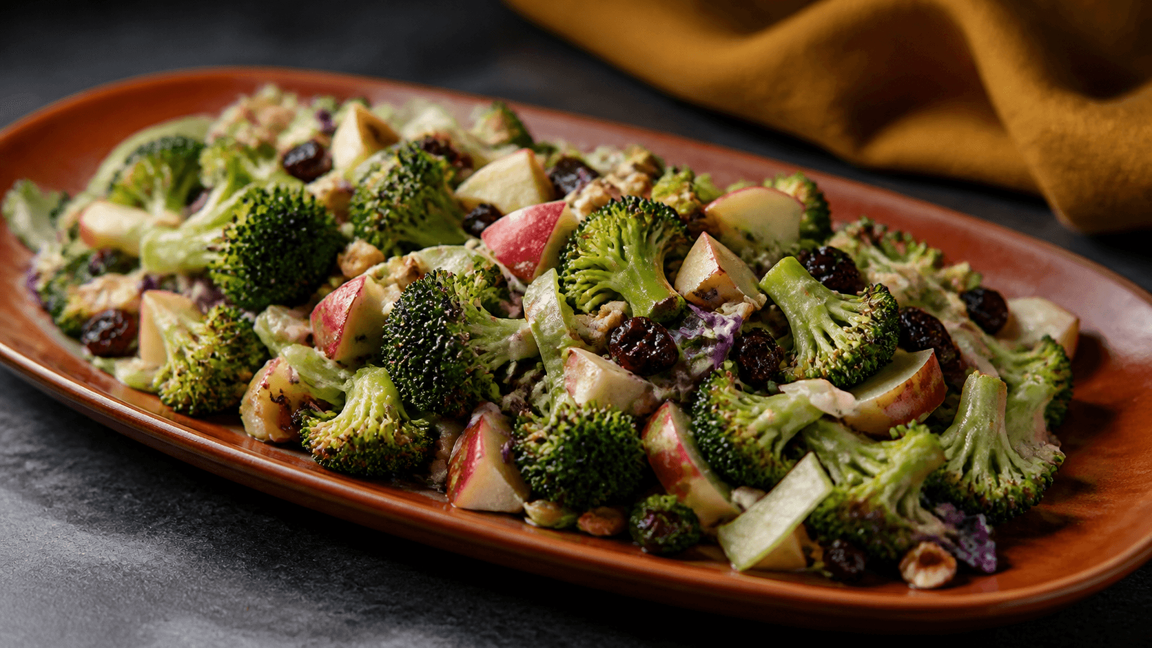 Brændt orange fad med ristede broccolibuketter, æble, rødkål, tranebær, hasselnødder og cremet senneps-nøddedressing