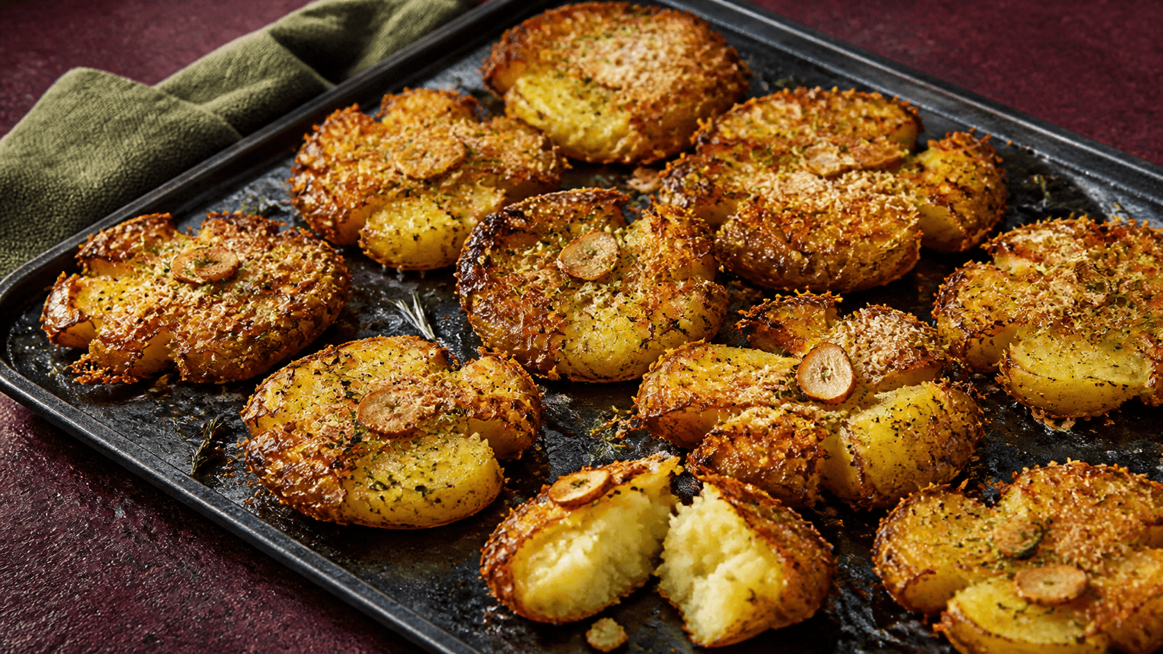 Mørk stålplade med ekstra sprøde knuste kartofler som gyldne rosetter, parmesan, ristede hvidløgschips, rosmarin og et åbent luftigt kartoffelcentrum