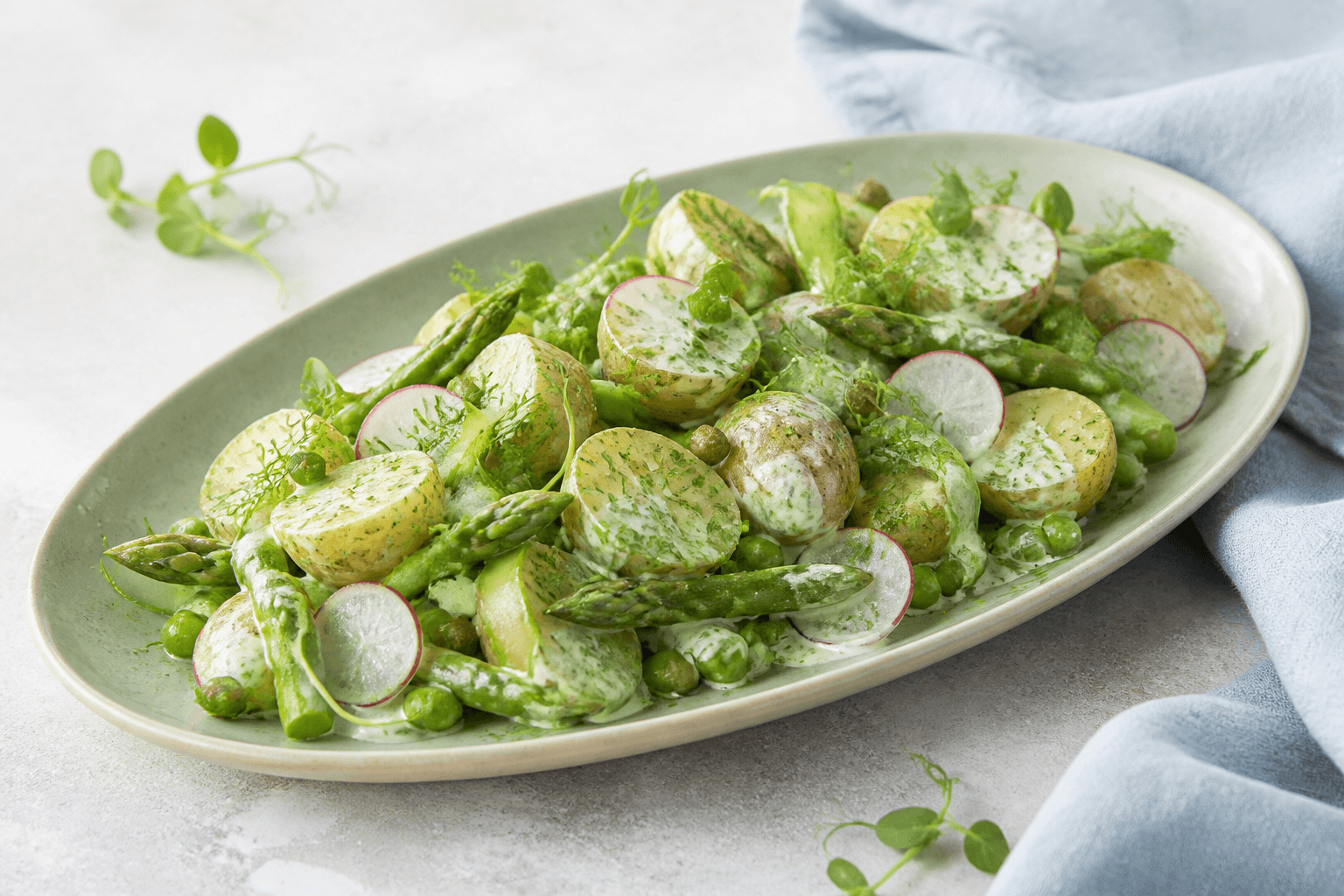 Grøn kartoffelsalat med nye kartofler, asparges, ærter, radiser, sukkerærter og cremet urtedressing på salviegrønt fad