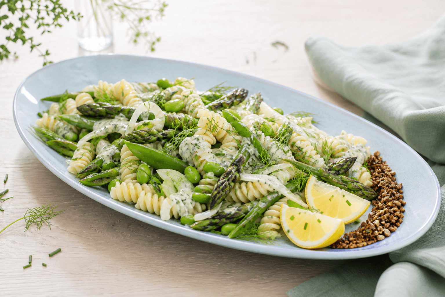 Pastasalat med fusilli, grillede asparges, sukkerærter, edamame, fennikel, dild-citrondressing og rug-solsikkeknas på lyseblåt fad