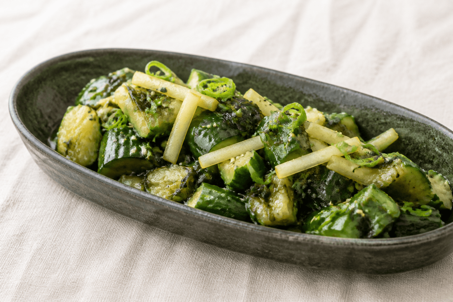 Asiatisk knust agurkesalat med pære, wakame, sesam og miso-limedressing i aflang mørkegrøn skål