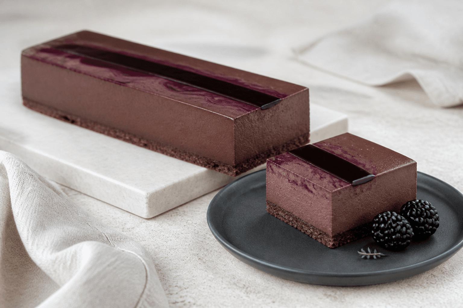 Rektangulær mørk chokoladecheesecake med rug-kakaobund, brombærmarmorering og blank brombær-misokaramel