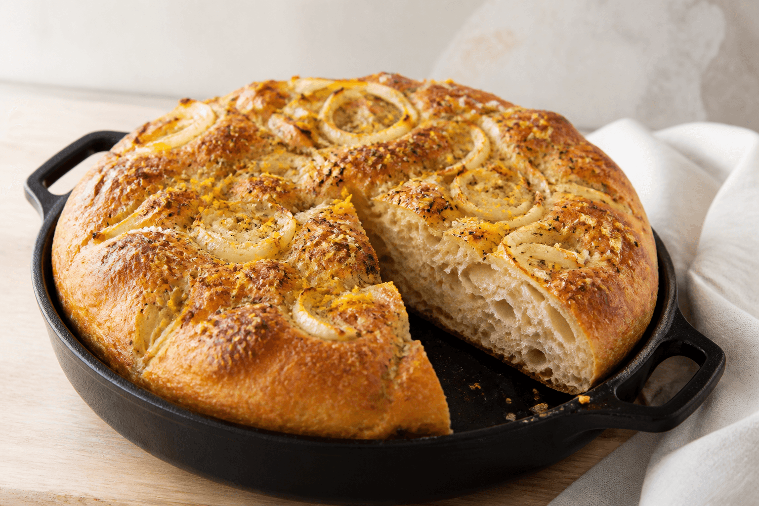 Rund koldhævet focaccia med karamelliseret fennikel, appelsinskal, sort peber og luftig krumme i støbejernspande