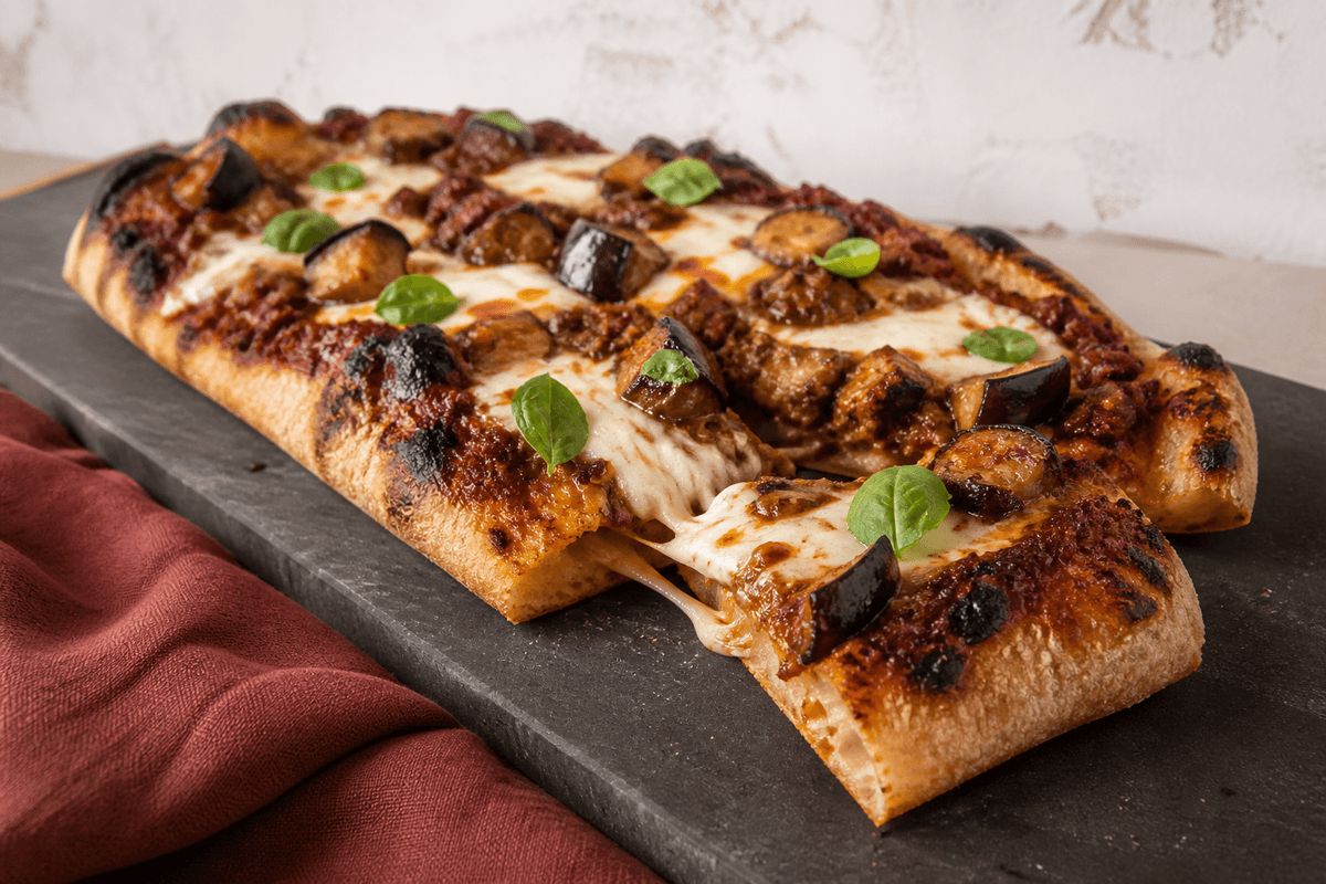 Aflang pizza bolo med okseragù, aubergine, fior di latte og basilikum-chiliolie på mørkt serveringsbræt