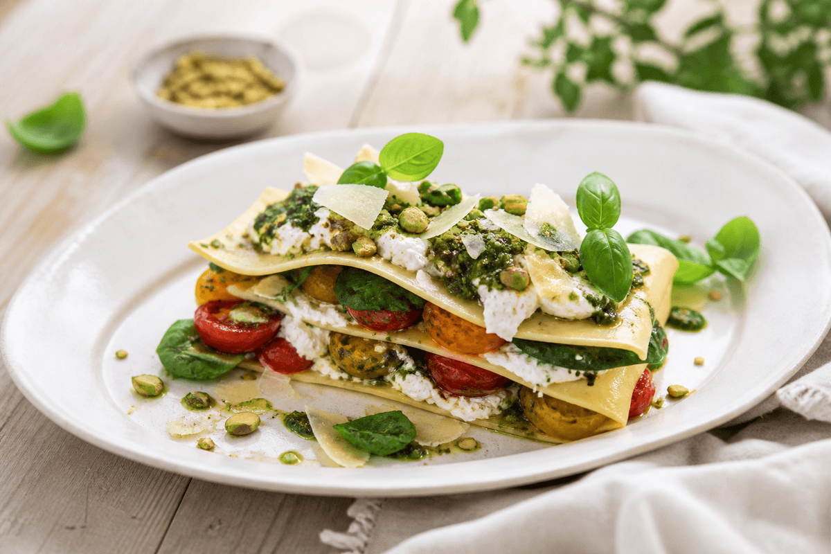 Åben sommerlasagne med ristede gule og røde tomater, citronricotta, basilikum-pistaciepesto, babyspinat, parmesan og pistacier