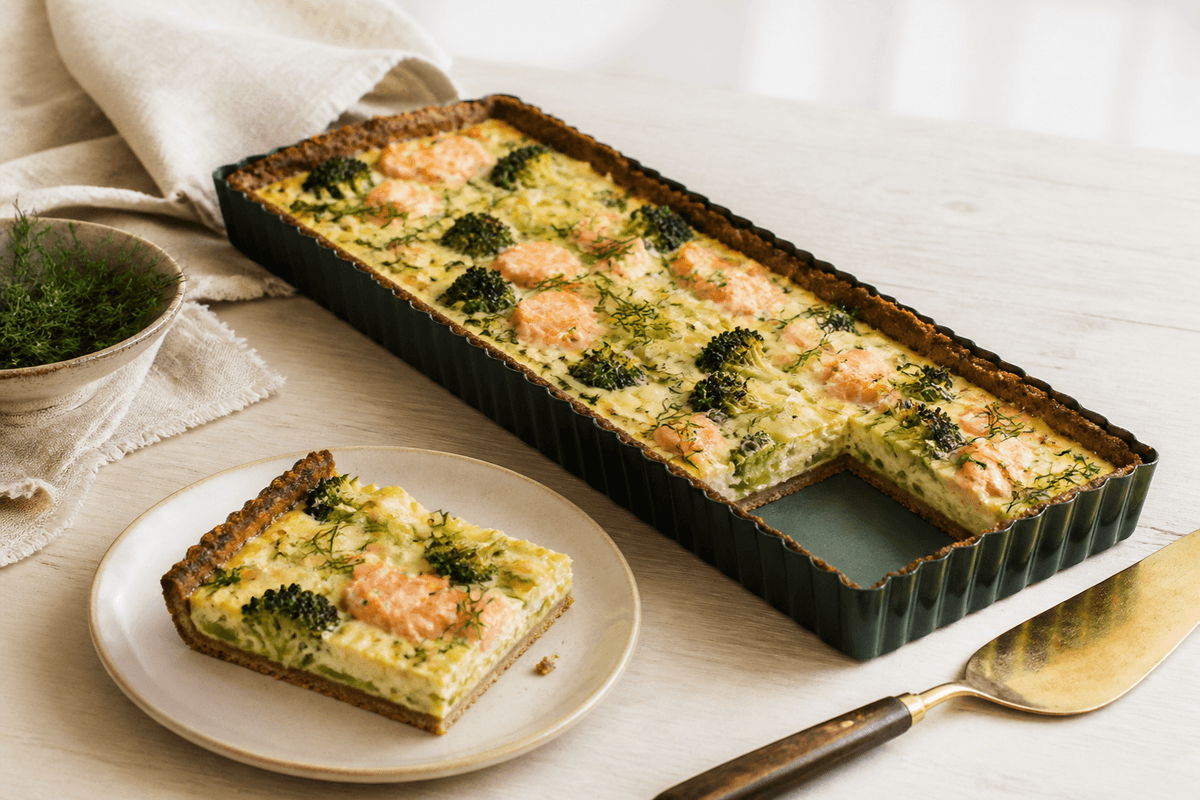 Rektangulær broccoli-laksetærte med sprød rugbund, porre, ricotta, citron og dild med et stykke løftet ud