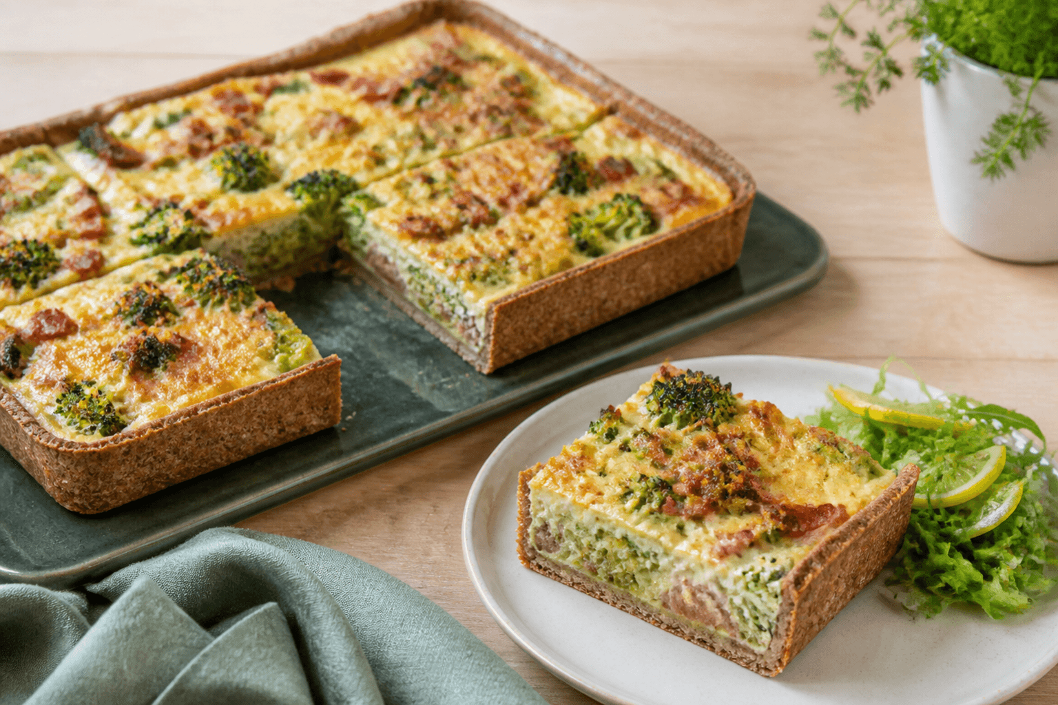 Rektangulær broccolitærte med høj fuldkorns-rugbund, broccoli, porre, røget bacon, cheddar og citronurtesalat på grønt fad