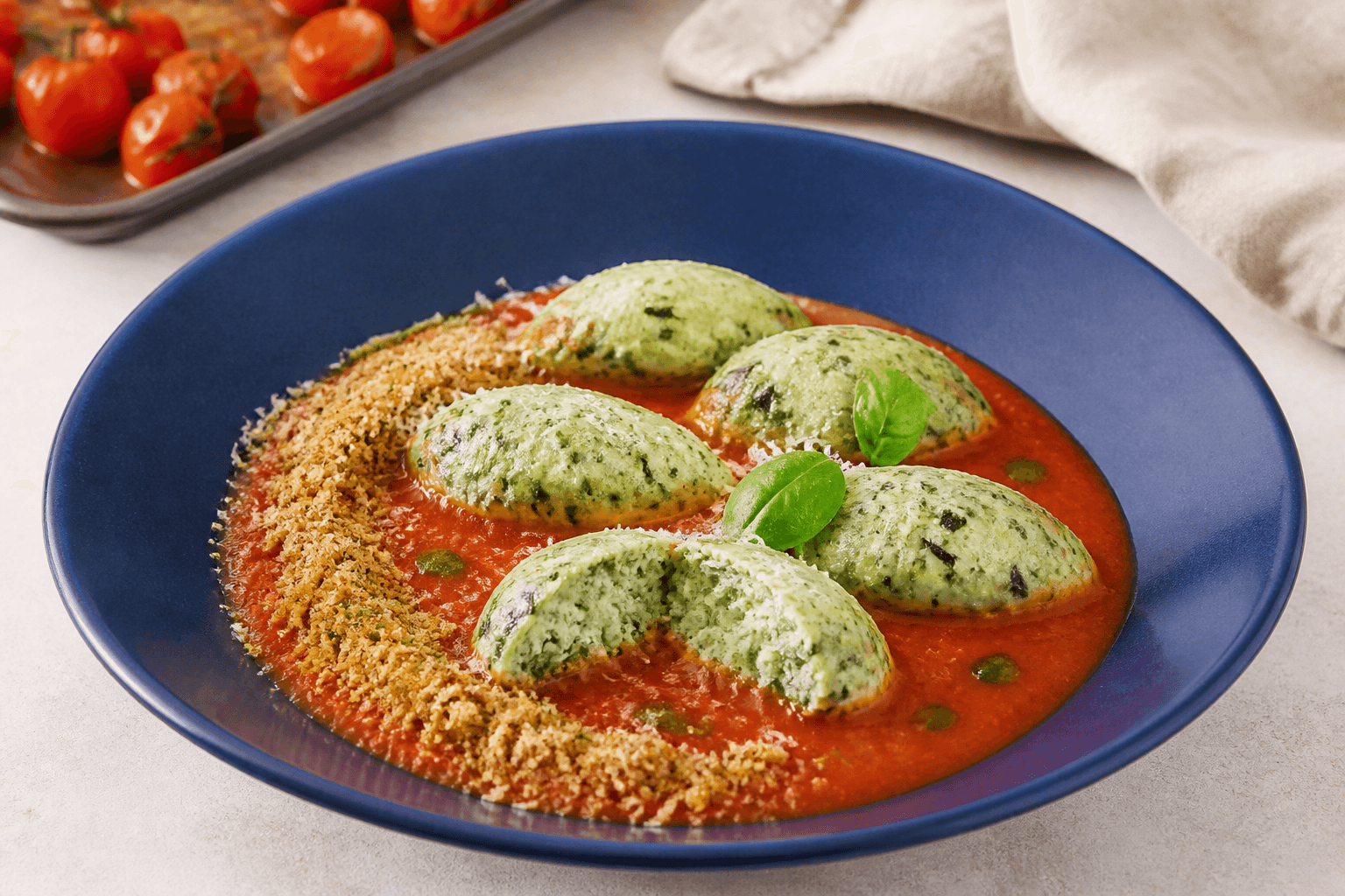 Fem grønne ricotta-malfatti og én overskåret i glat ristet tomat-fennikelsauce med citronpangrattato, basilikumolie og lagret ost i blå skål
