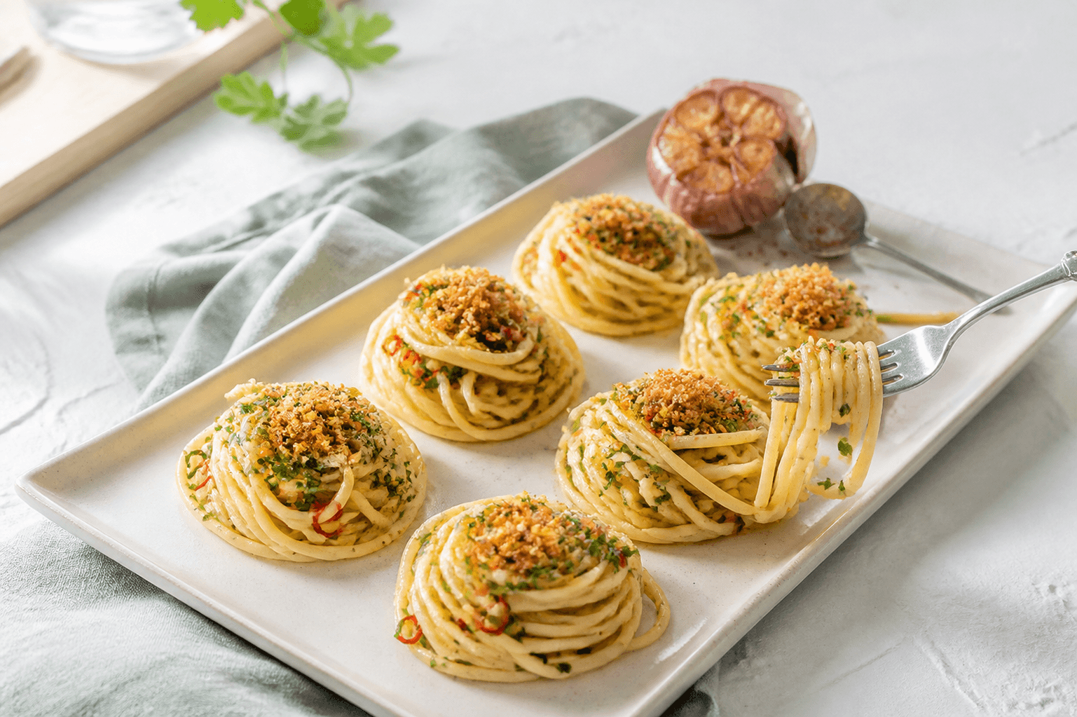 Seks blanke reder linguine aglio e olio med ristet hvidløg, persille, citron, chili og sprødt surdejsdrys på et langt elfenbensfad