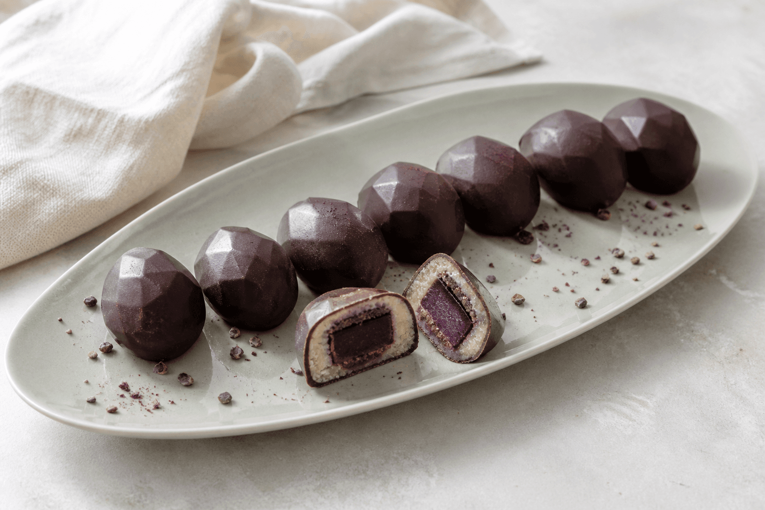 Facetterede marcipanpåskeæg med mørk chokolade, solbærganache og sprød rugpraliné på lysegrønt fad