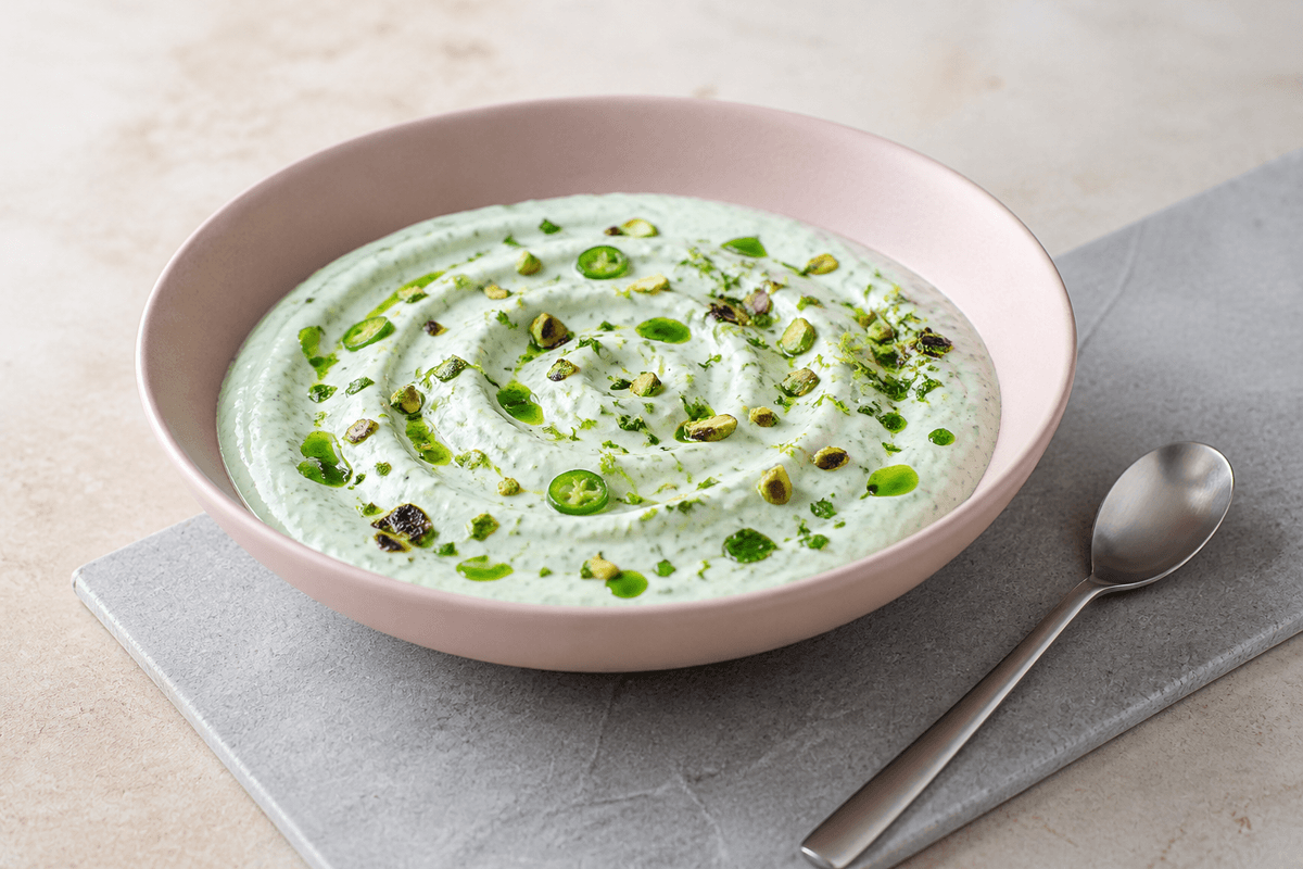 Lysegrøn mynte-korianderdip med lime, grøn chili, urteolie og pistacie i bred rosa skål