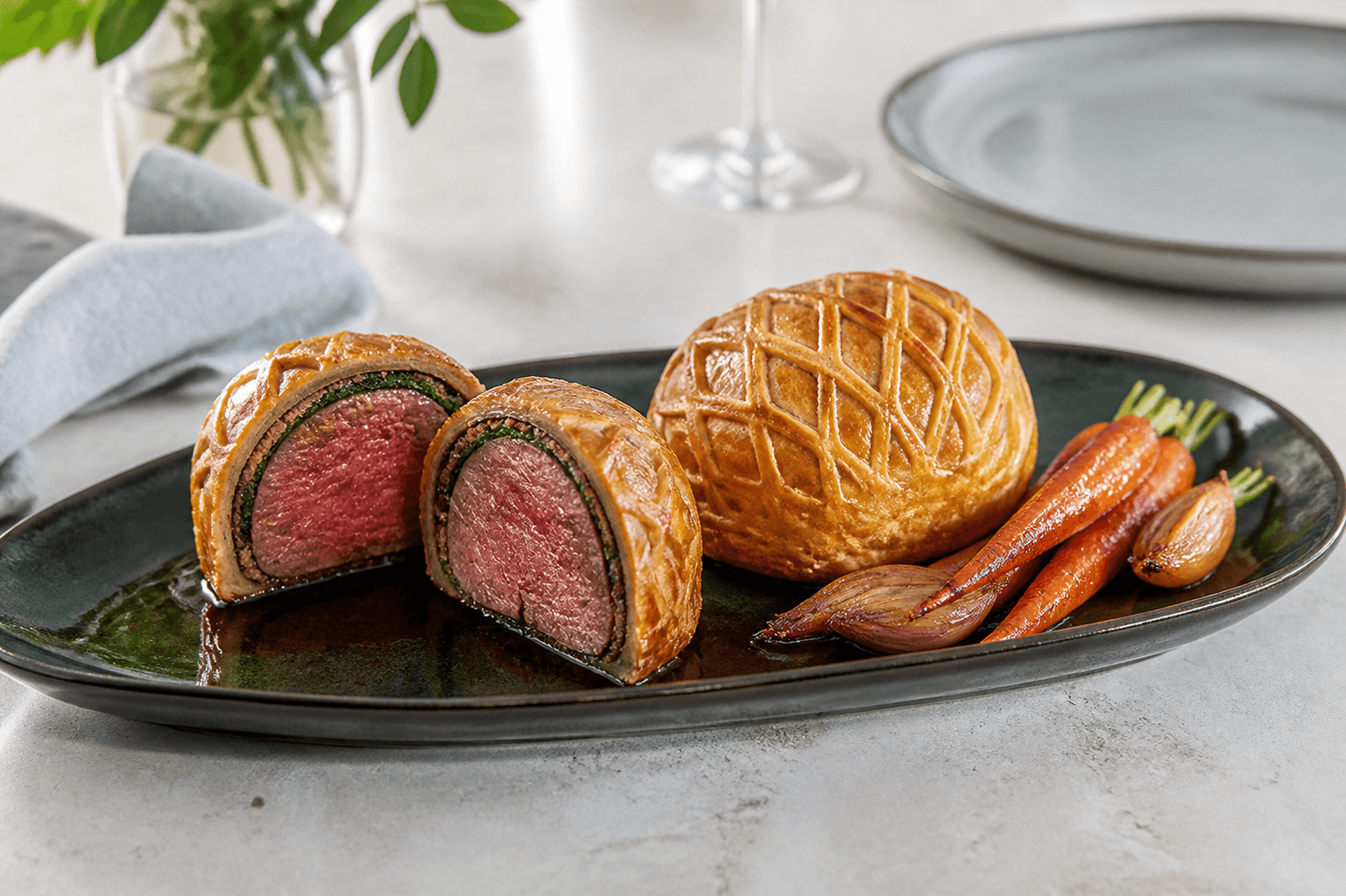 Individuelle Beef Wellington med gylden fletdej, rosa oksemørbrad, mørk porciniduxelles og tynd grøn spinatcrêpe på mørkegrønt fad
