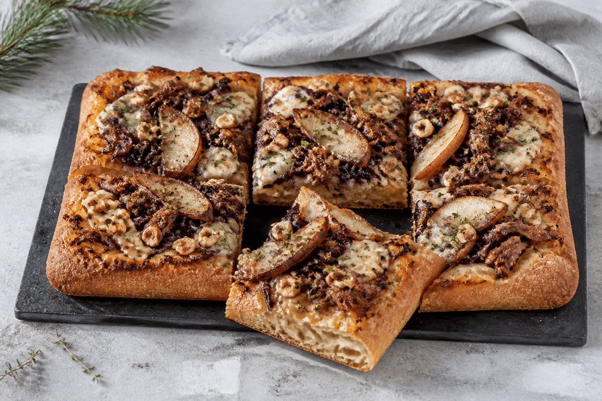 Rektangulær julepizza med confiteret and, rødkål, stegt pære, blåskimmelost, hasselnød og orange-timiangremolata på sort plade