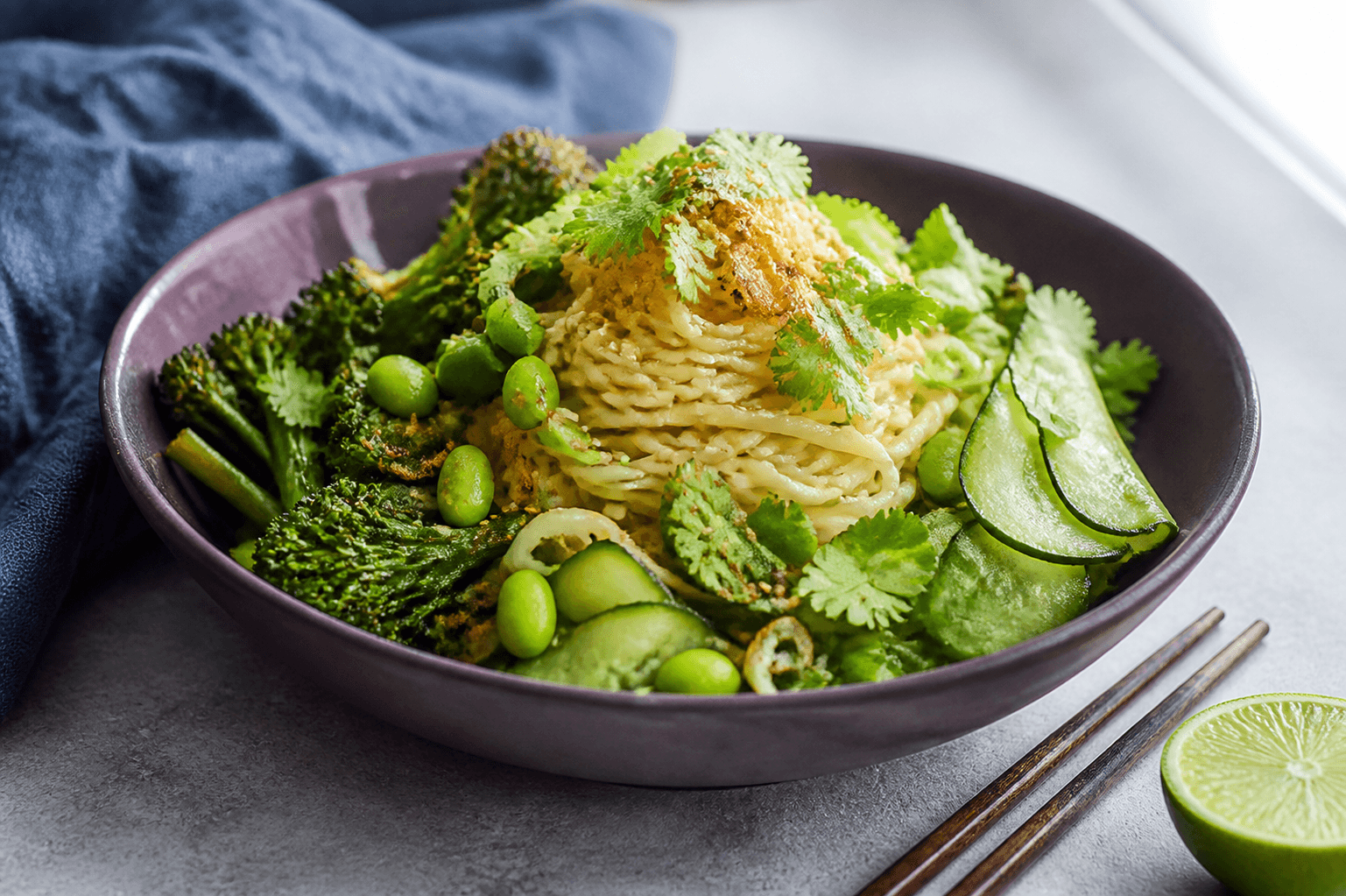 Miso-limenudler med edamame, grillet broccolini, agurkebånd, koriander og sprøde skalotteløg i auberginefarvet skål