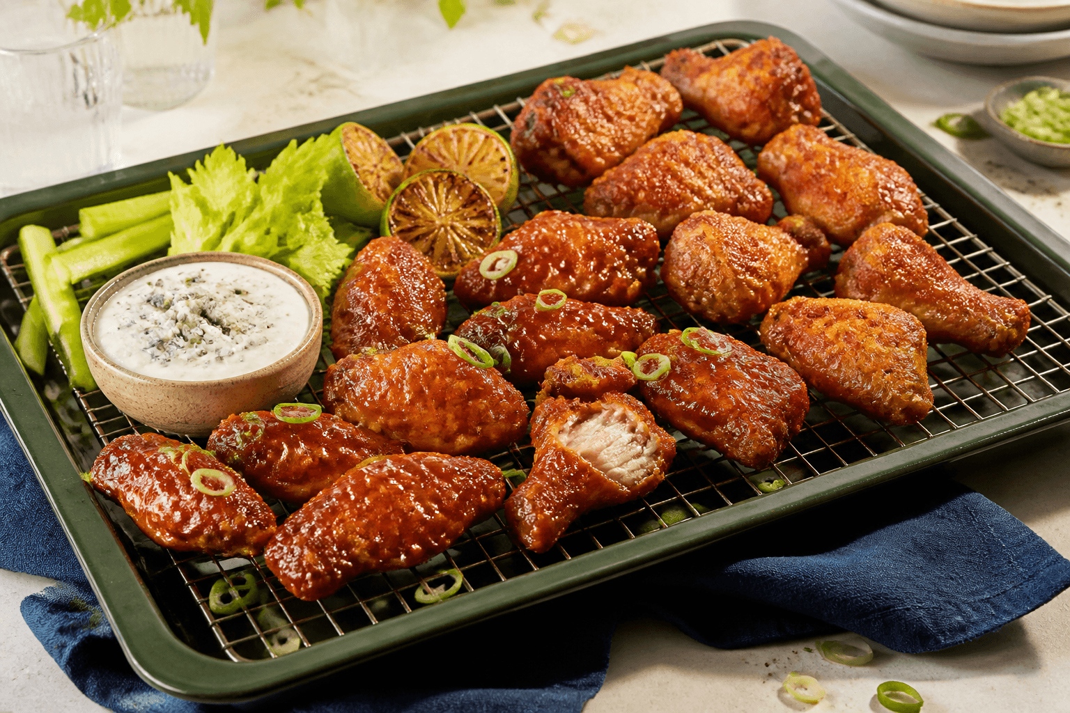 Mørkegrønt fad med sprøde hotwings på rist, fermenteret chiliglace, blåost-skyrdip, selleri, agurk, lime og forårsløg