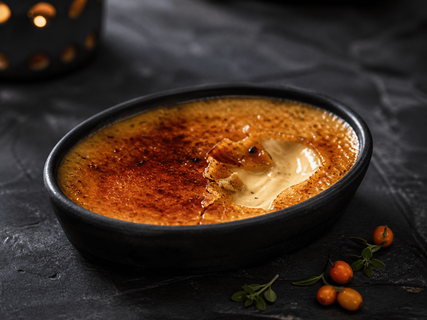 Mørk oval crème brûlée med tynd ravgylden karamelskorpe, havtorn, citrontimian og enkelte kardemommefrø i nordisk sidelys