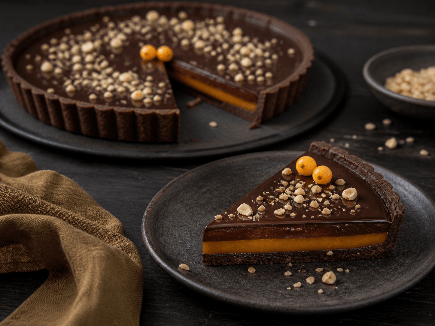 Elegant skive mørk chokoladetærte med rug-kakaobund, klart orange havtornkaramel, espresso-ganache og ristede hasselnødder