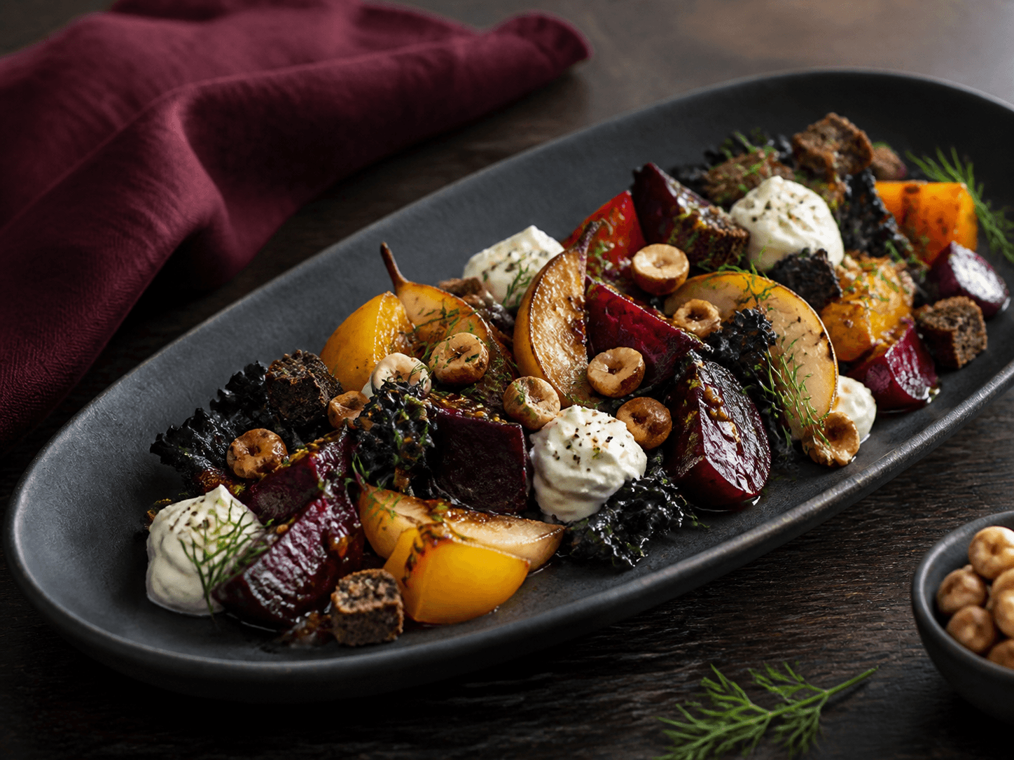 Langt sort fad med bagte røde og gule rødbeder, karamelliseret pære, pisket feta-peberrod, sortkål, rugcroutoner, hasselnød og dild