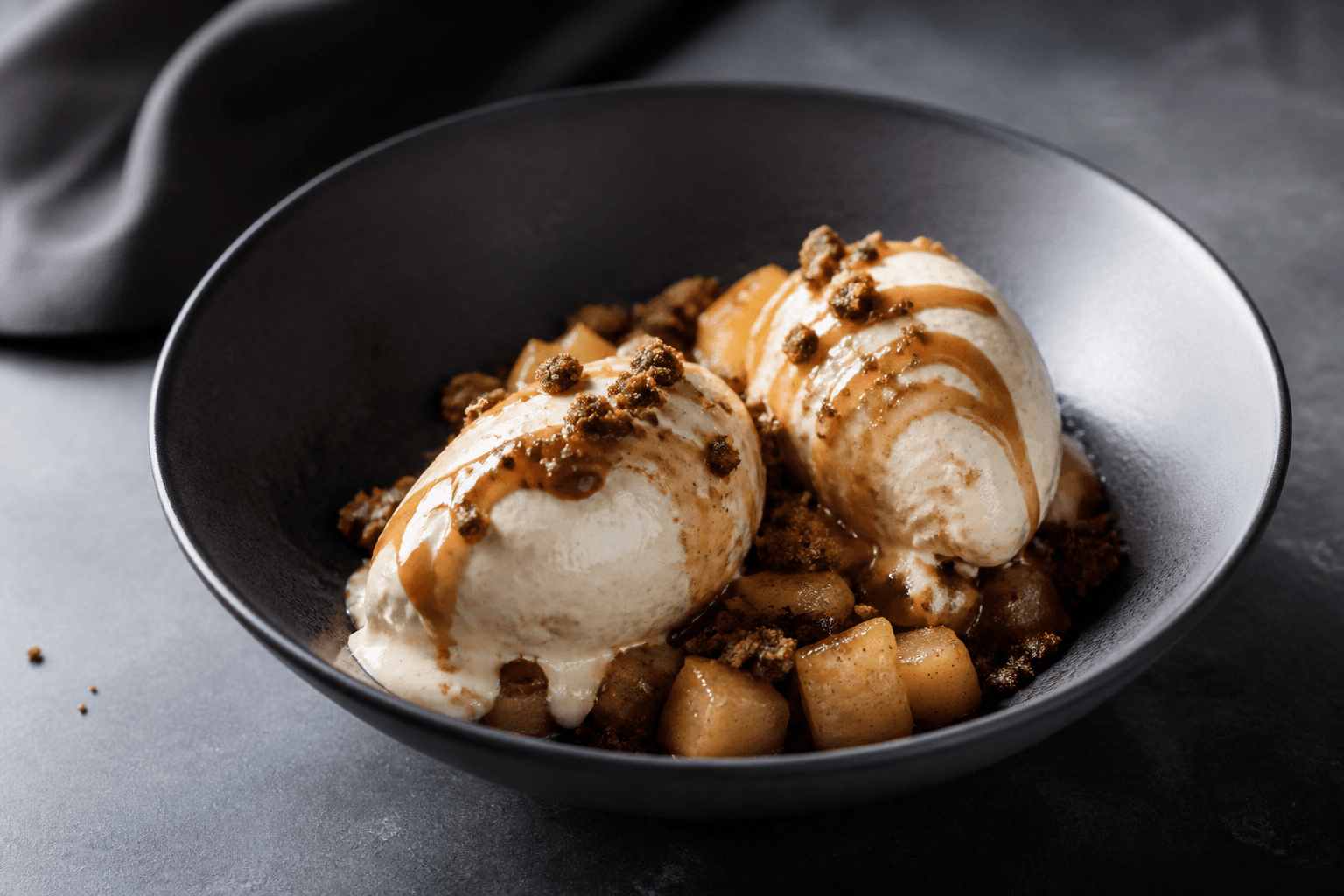 Kærnemælksis med maltkaramel, bagte pæretern og mørkt rugknas i sort dessertskål