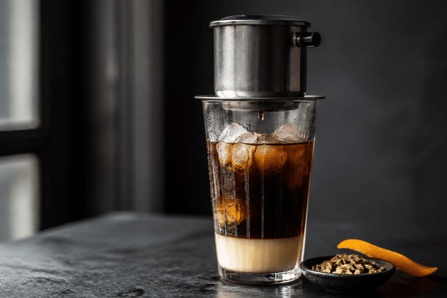 Lagdelte vietnamesisk iskaffe i højt rillet glas med kondenseret mælk, mørk robustakaffe, kaffeisterninger og phin-filter