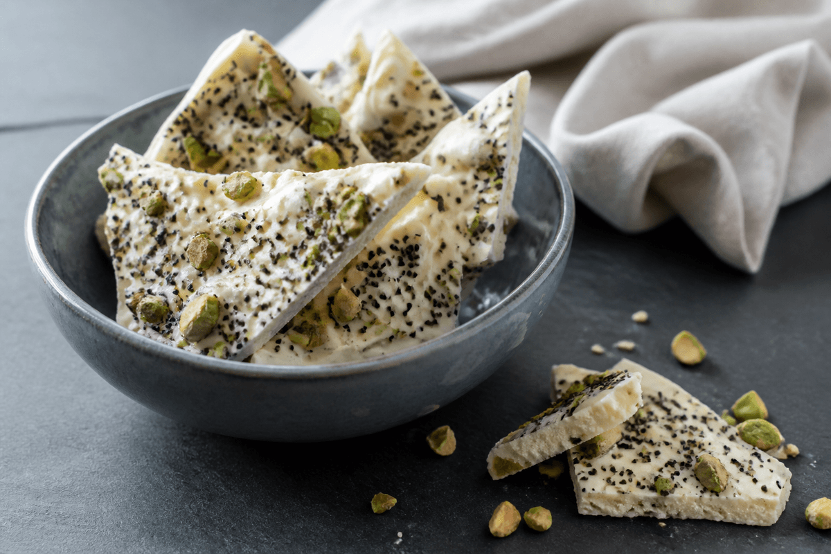Hvidt chokoladebrud med pistacie og lakrids fotograferet i en selvstændig nordisk servering med tydelig realistisk tekstur og rettens vigtigste råvarer