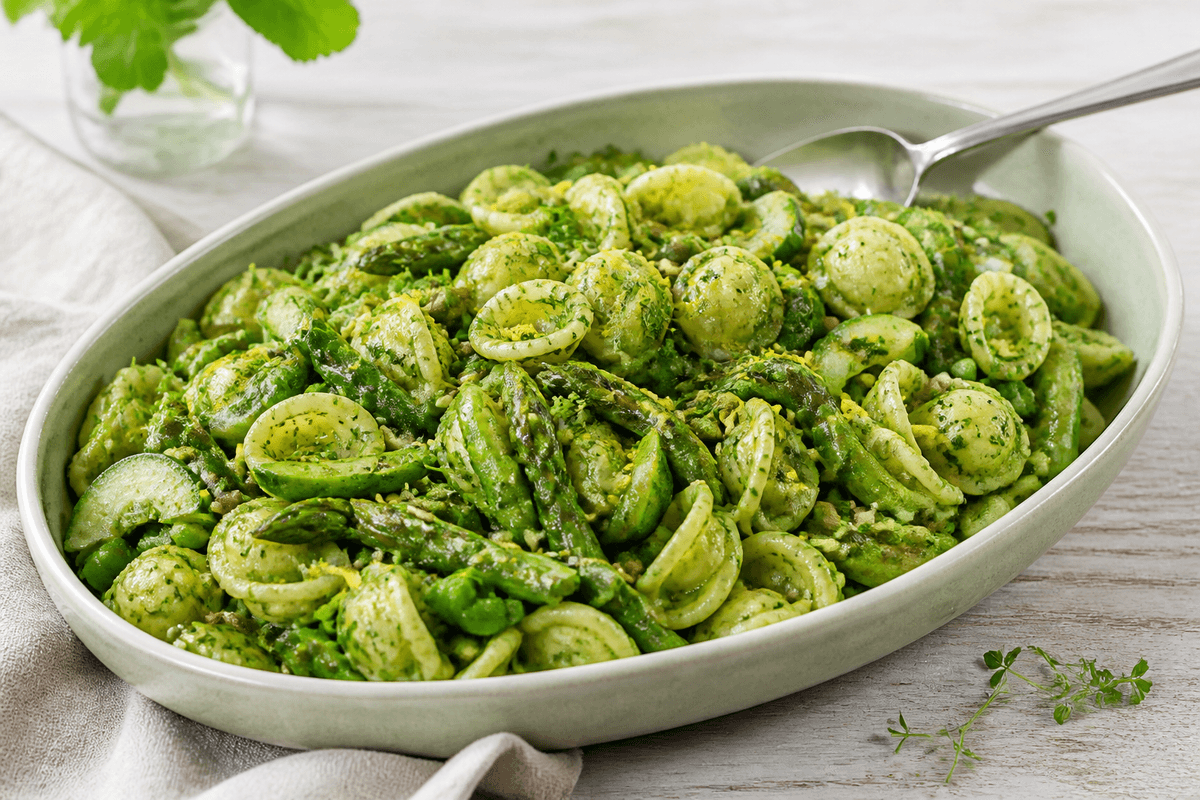 Grøn orecchiette-pastasalat med asparges, ærter, agurk, sukkerærter, spinat og cremet urtedressing på salviegrønt fad