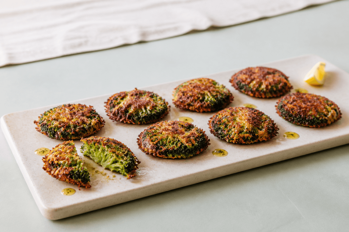 Otte knuste broccoli-rosetter i to rækker på sandfarvet fad med sprød cheddarhalo, røget paprika, citronolie og ét åbent stykke