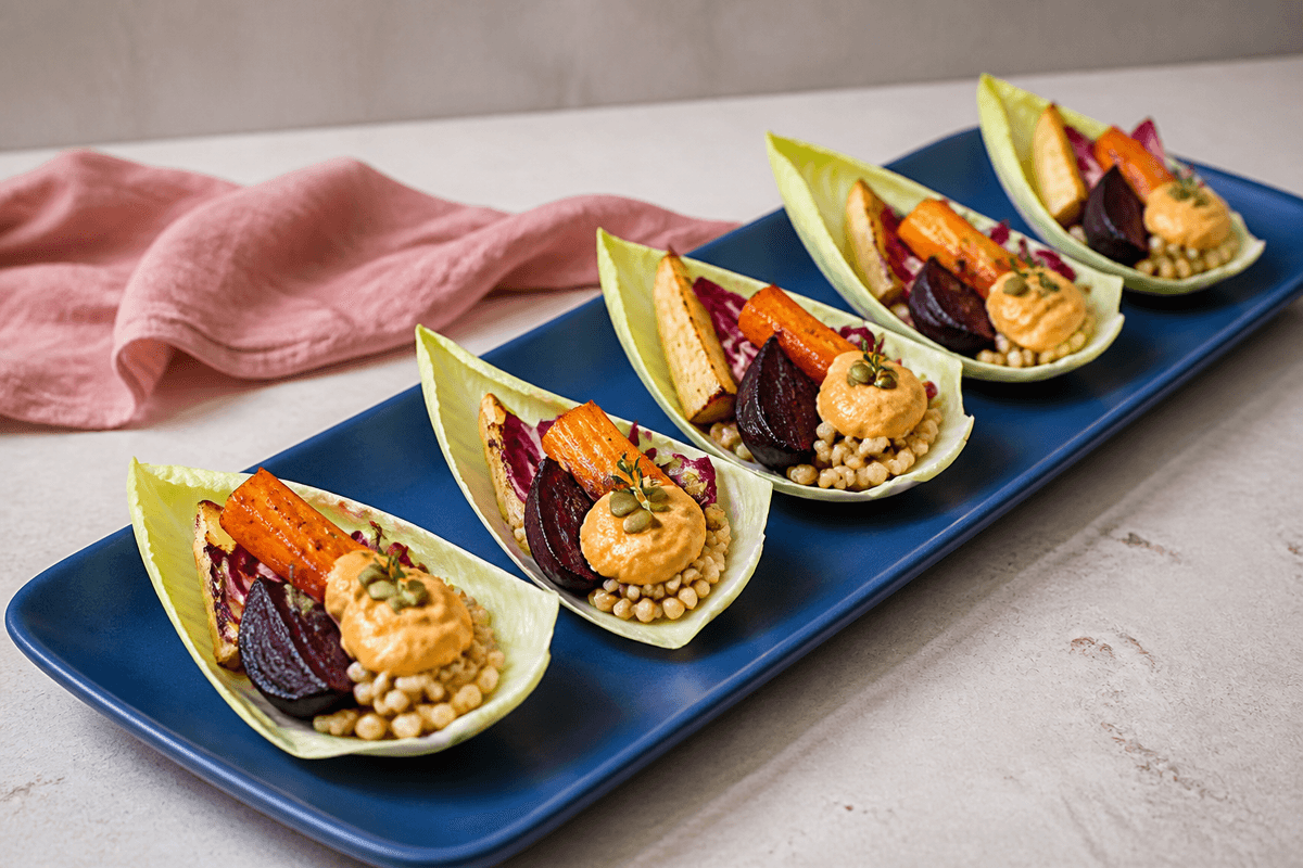 Fem spidskålsbåde på koboltblåt fad med bagte rødbeder, gulerødder, pastinak, perlebyg, radicchio, orange-tahinidressing, græskarkerner og timian