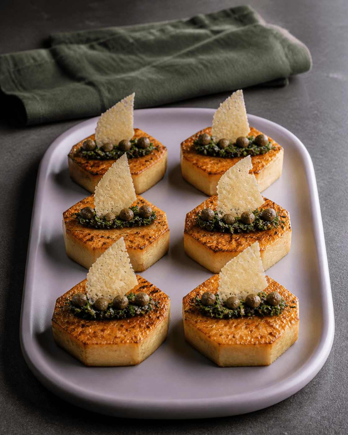 Seks sekskantede knoldselleristeaks på lavendelfad med urte-kapersgremolata, kapers og parmesansejl