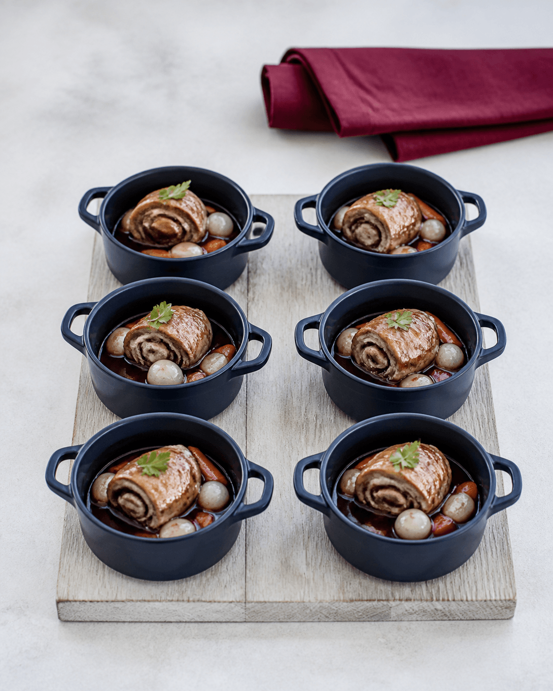 Seks marineblå cocotter med coq au vin, kyllingeroulade, rødvinssauce, perleløg, svampe, gulerod og persille
