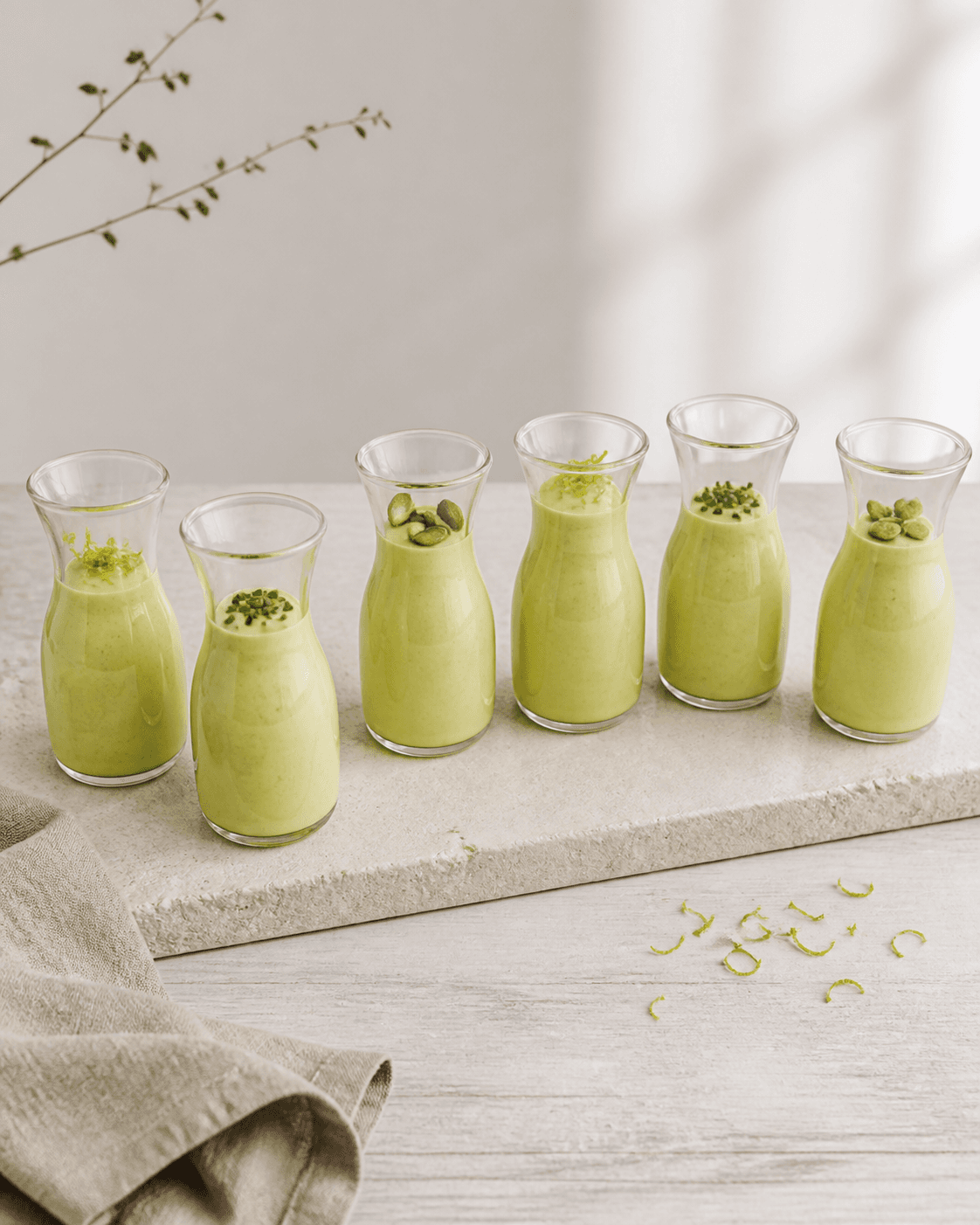 Seks små glaskarafler med lysegrøn avocadodressing, lime, purløg og græskarkerner