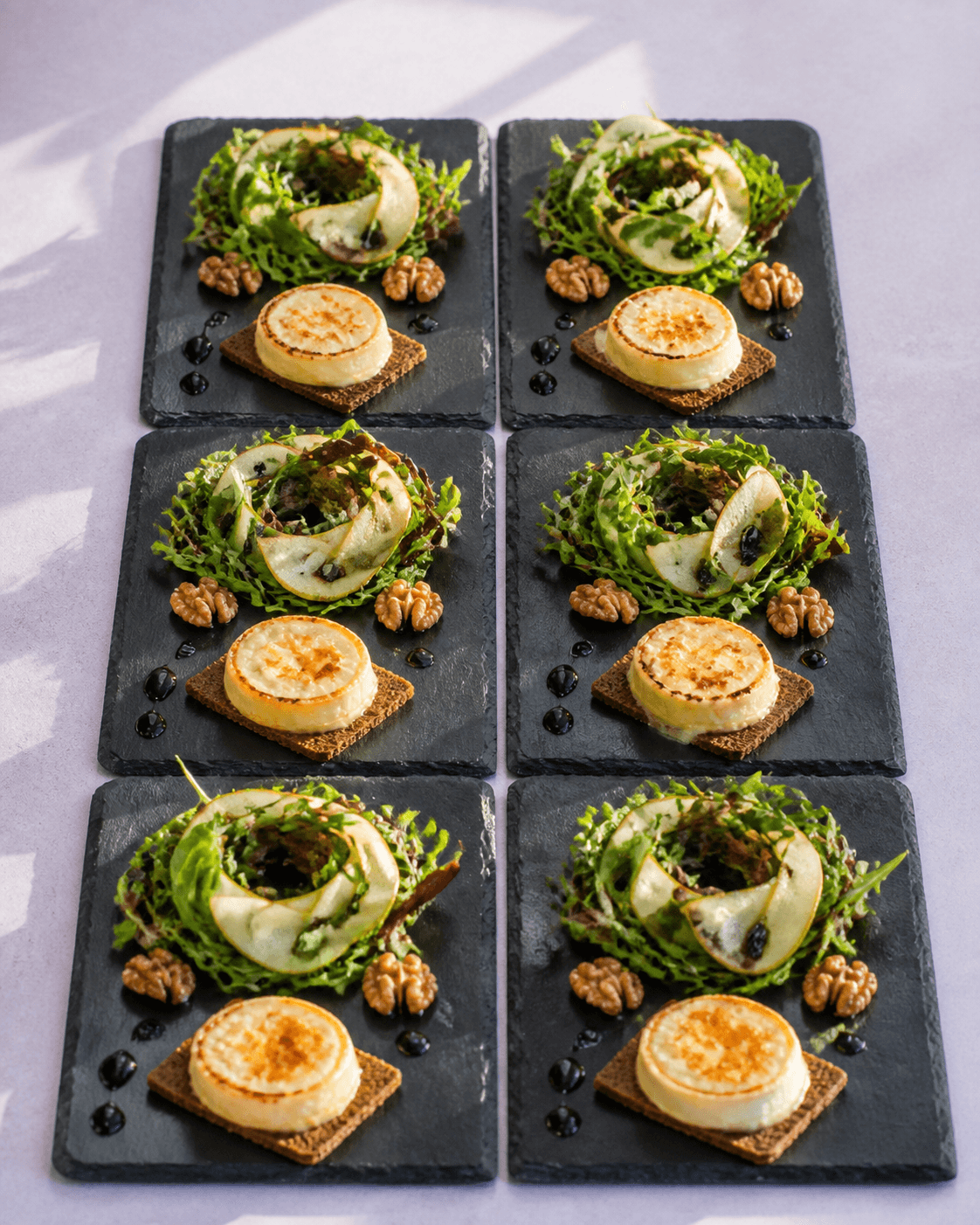 Seks skiferfliser med grøn salatring, pære, gratineret gedeost på boghvedeknæk, valnødder og vinaigrette