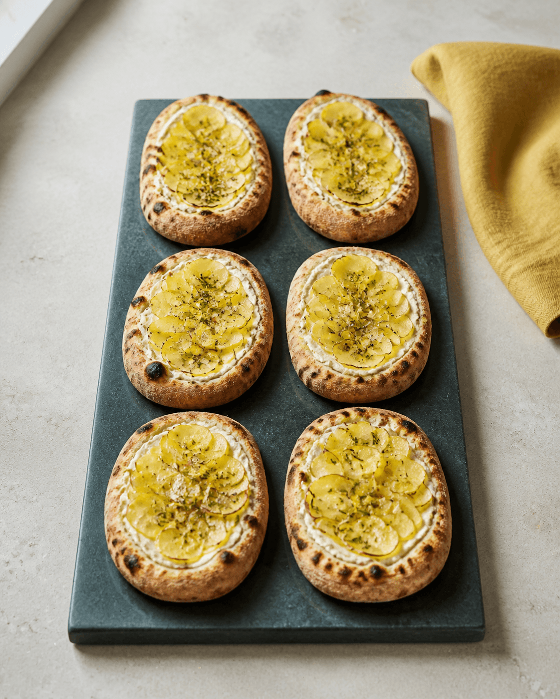 Seks ovale minipizzaer med mascarpone, kartoffelroset, rosmarin, citron og gylden blæret kant