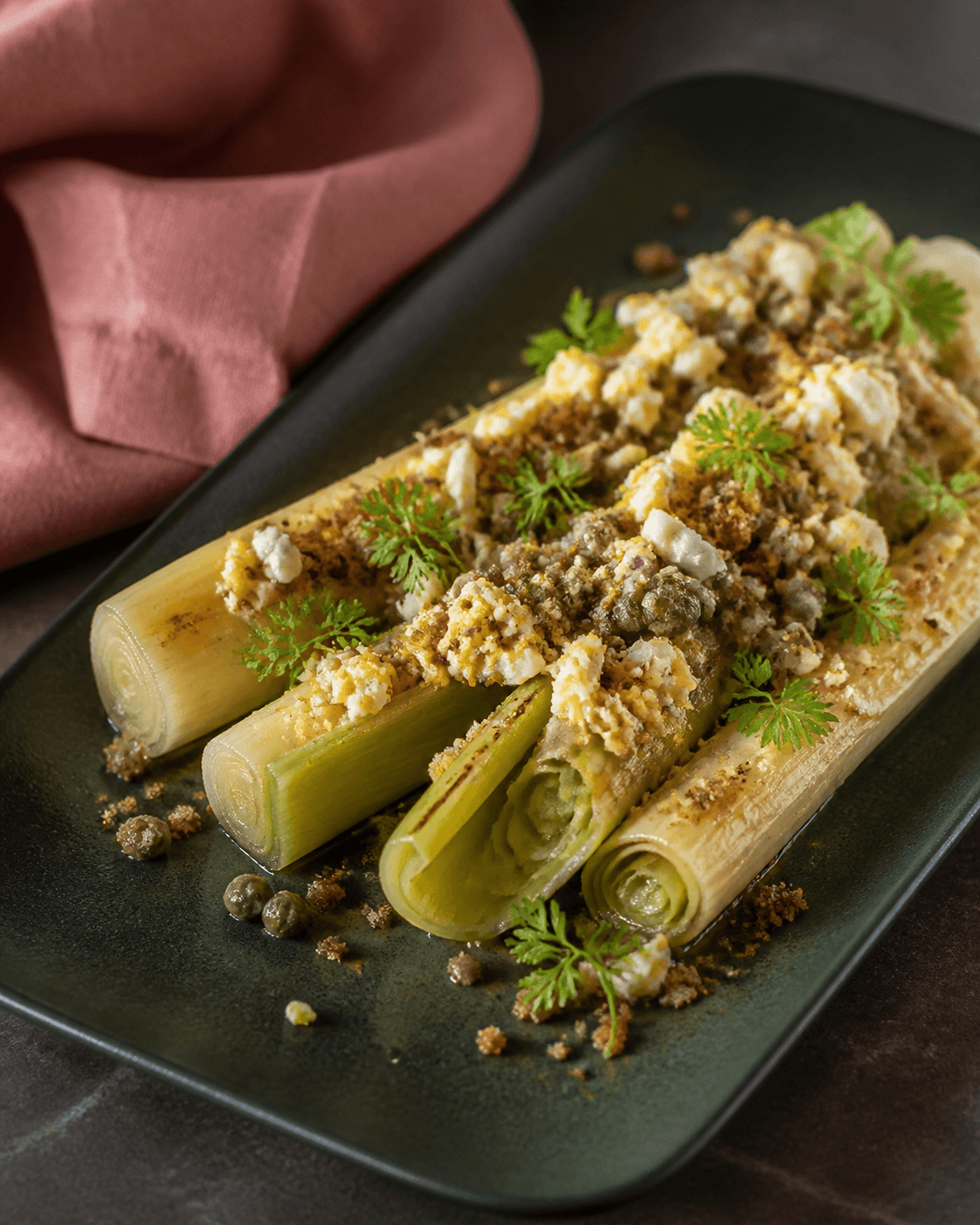 Braiserede og grillede porrer med kapervinaigrette, jammy æg, kørvel og rugknas på skovgrønt fad