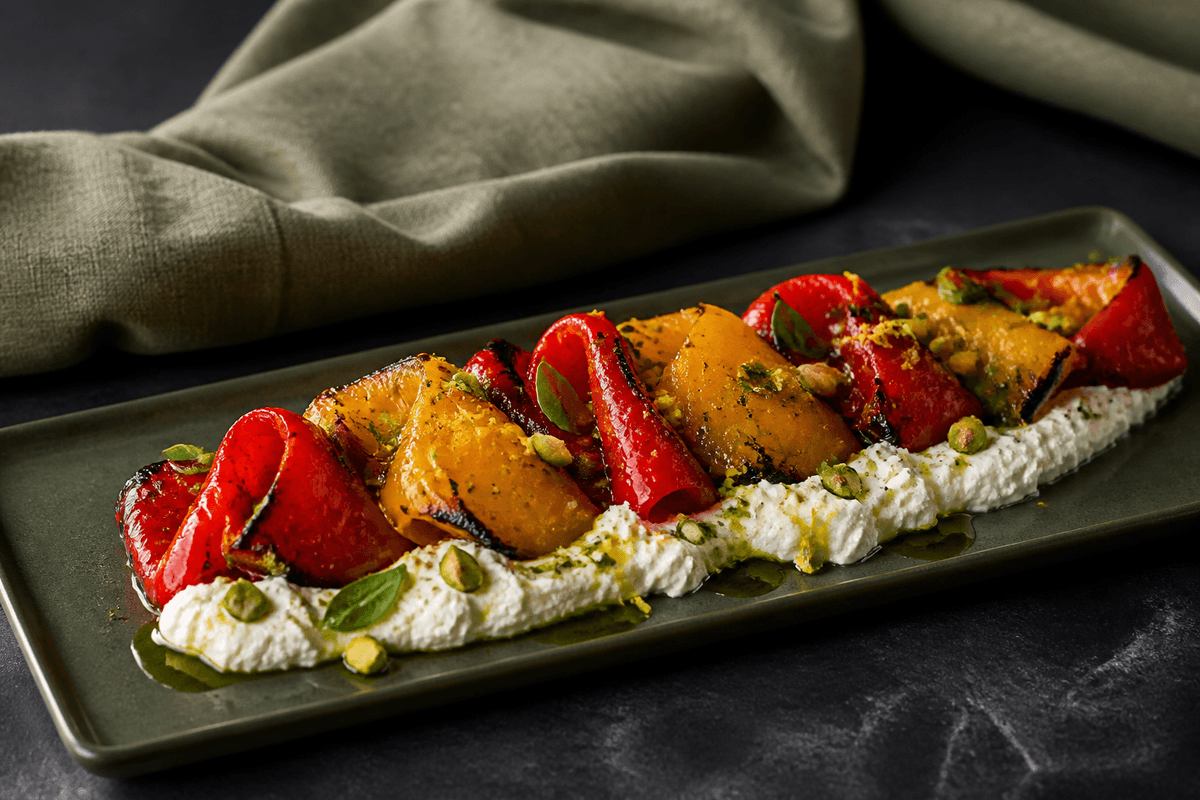 Grillede peberfrugter med ricotta og pistacie anrettet i Madblikkets lyse nordiske billedstil med rettens vigtigste råvarer tydeligt synlige