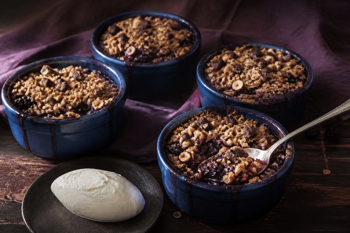 Solbærcrumble med chokolade, hasselnød og rug anrettet i Madblikkets lyse nordiske billedstil med rettens vigtigste råvarer tydeligt synlige