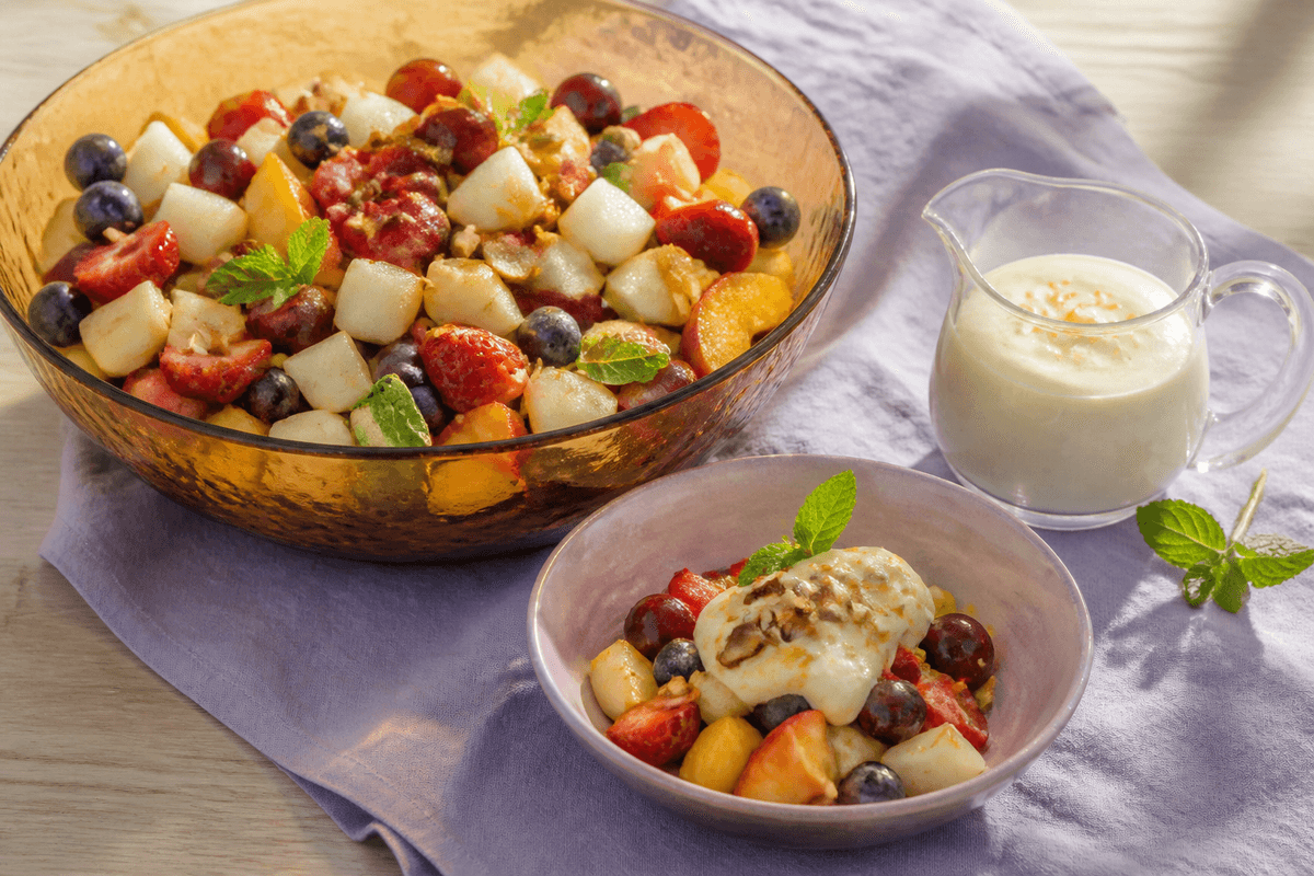 Frugtsalat med citrus-råcreme og mandelknas anrettet i Madblikkets lyse nordiske billedstil med rettens vigtigste råvarer tydeligt synlige