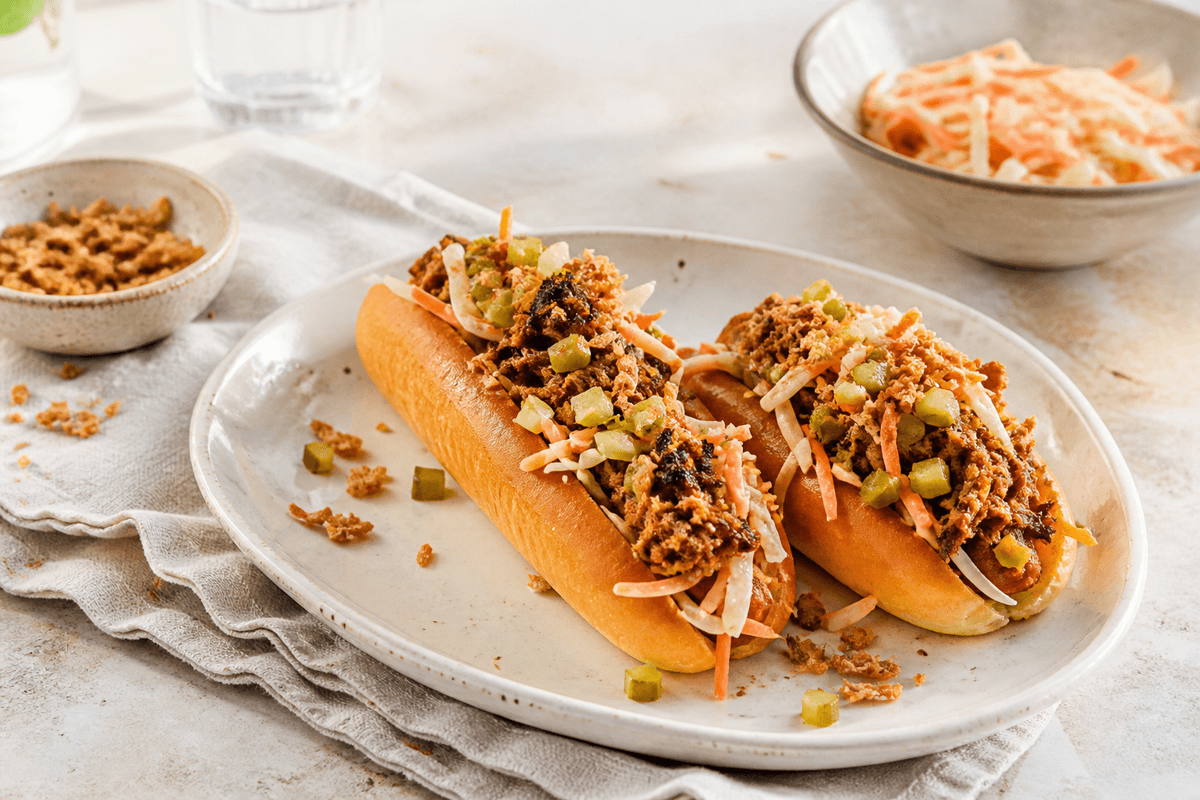 Pulled pork-hotdog med syltet kål og sprøde løg anrettet i Madblikkets lyse nordiske billedstil med rettens vigtigste råvarer tydeligt synlige