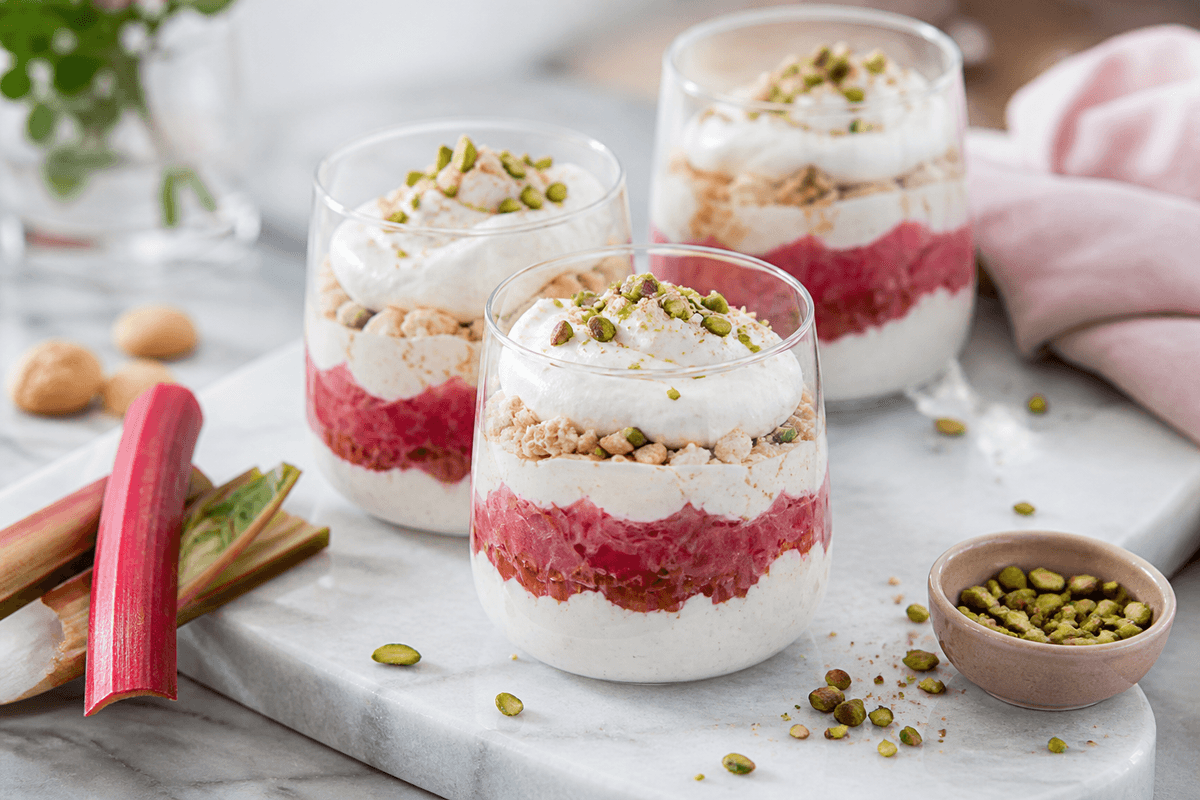 Rabarbertrifli med makroner, vaniljeskum og pistacie anrettet i Madblikkets lyse nordiske billedstil med rettens vigtigste råvarer tydeligt synlige