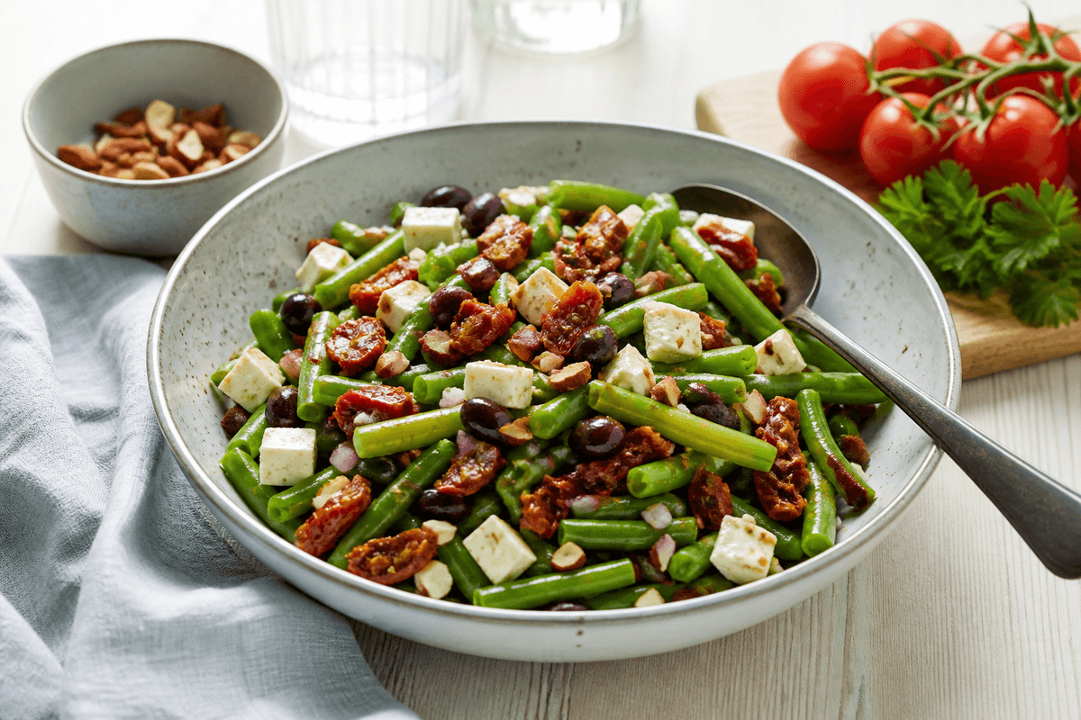 Bønnesalat med grønne bønner, feta og soltørrede tomater anrettet i Madblikkets lyse nordiske billedstil med rettens vigtigste råvarer tydeligt synlige