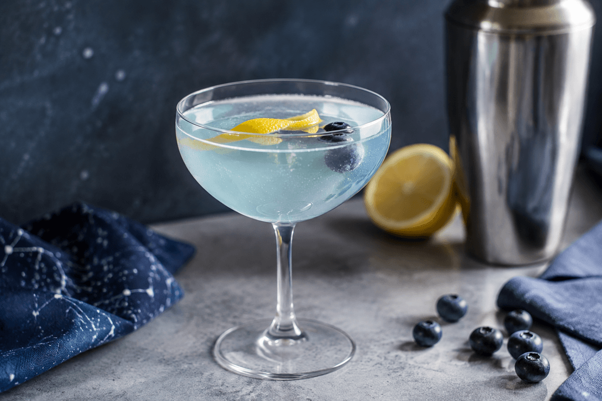 Lyseblå Astronaut drink i coupeglas med citronspiral, bobler og tre blåbær