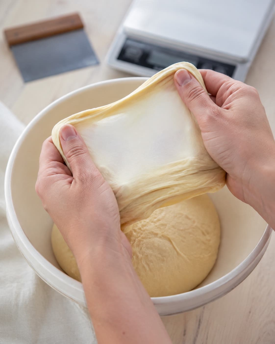 Elastisk kardemommedej trækkes til et tyndt intakt glutenvindue over skålen