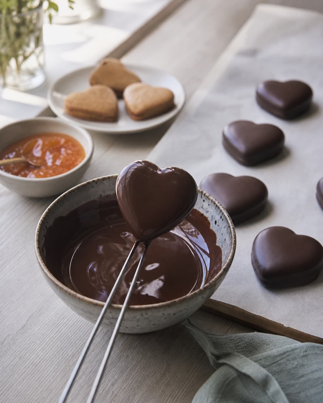 sammenlagte honninghjerter dyppes i blank mørk chokolade og sættes enkeltvis på bagepapir; kontroltegnet er skallen er tynd og blank, og hjertet under føles blødt uden lækage