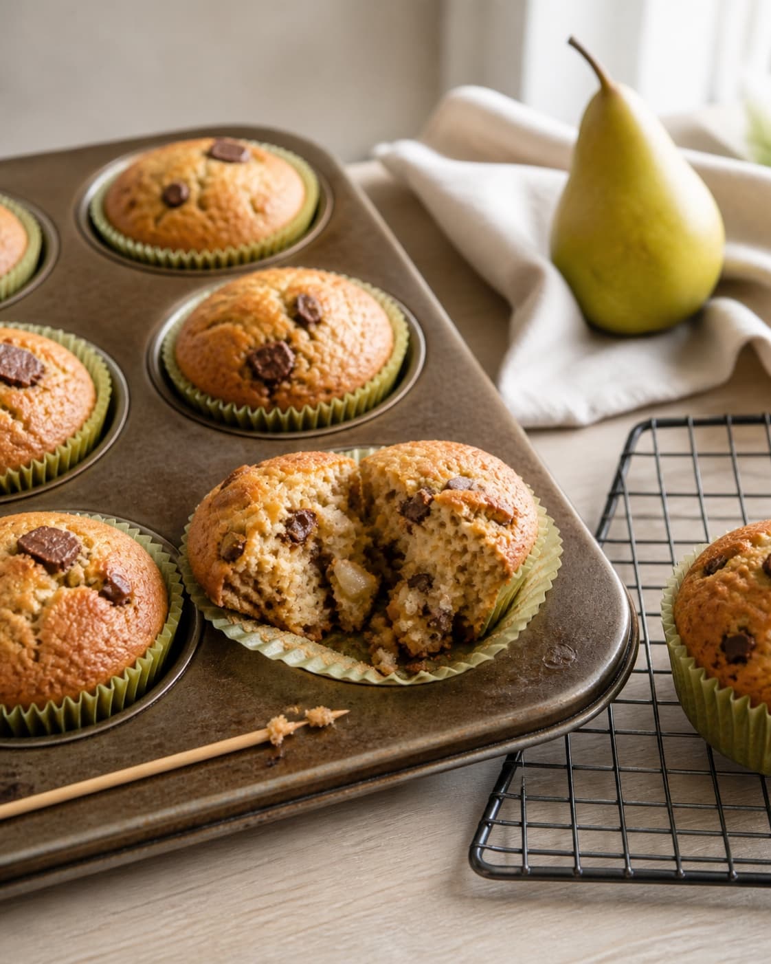gyldne kuplede pæremuffins på plade og rist, hvor én åben muffin viser sat fugtig krumme og en ren træpind har få fugtige krummer; kontroltegnet er muffinsene er gyldne, kuplede og mindst 96 °c uden våd dej